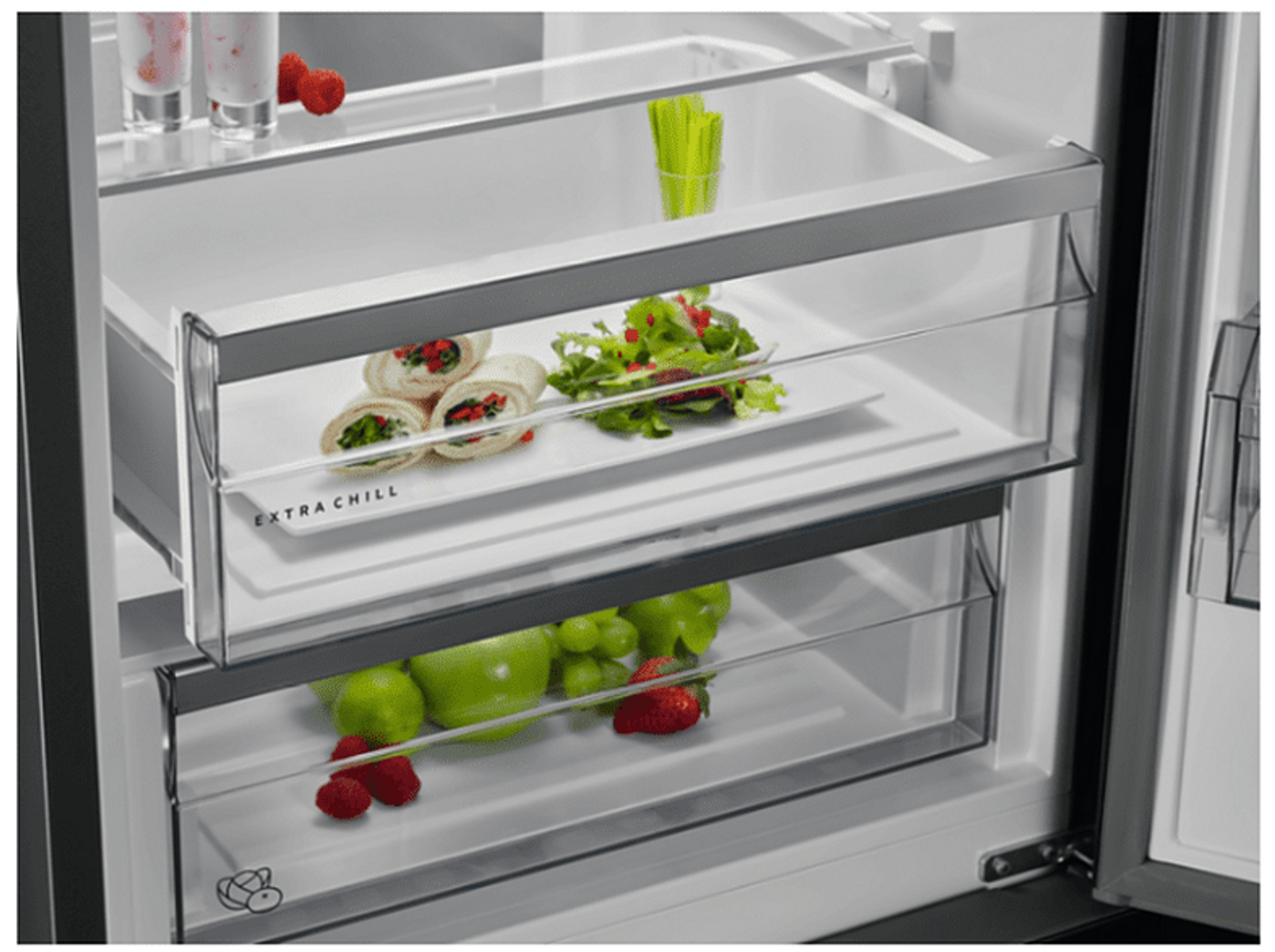 Zbliżenie na szufladę lodówki z jedzeniem, w tym wrapami i owocami.