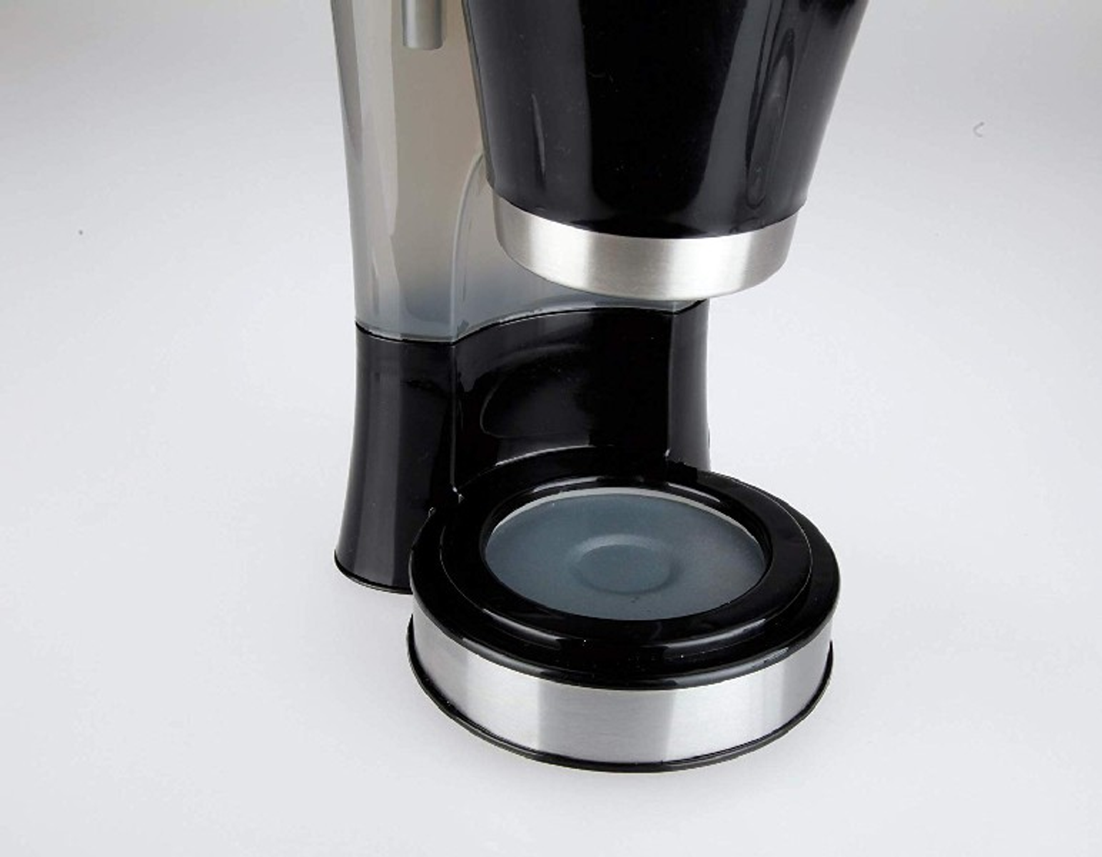 Macchina da caffè, primo piano sulla parte anteriore. Colore nero e argento, su una superficie bianca.