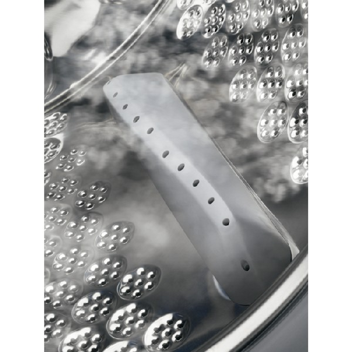 Primer plano del tambor de una lavadora con un generador de vapor. Vapor visible en el interior.