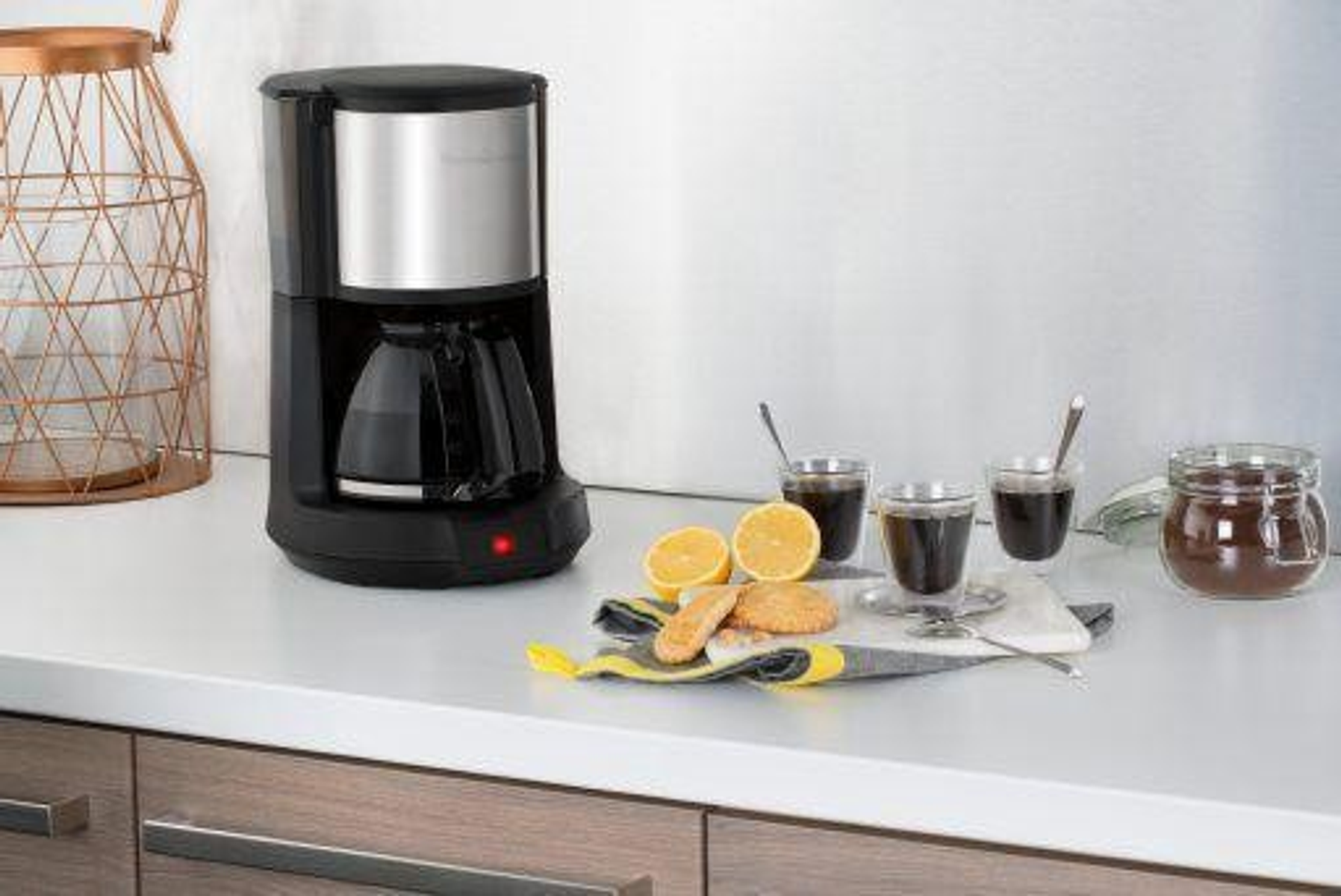 Una caffettiera con una caraffa, fette di limone, biscotti e bicchieri di vetro.