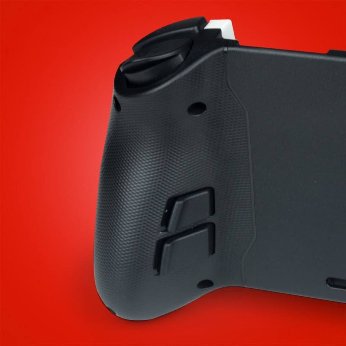 Nahaufnahme eines schwarzen Gamecontrollers, zeigt den hinteren Griff und Knöpfe auf rotem Hintergrund.