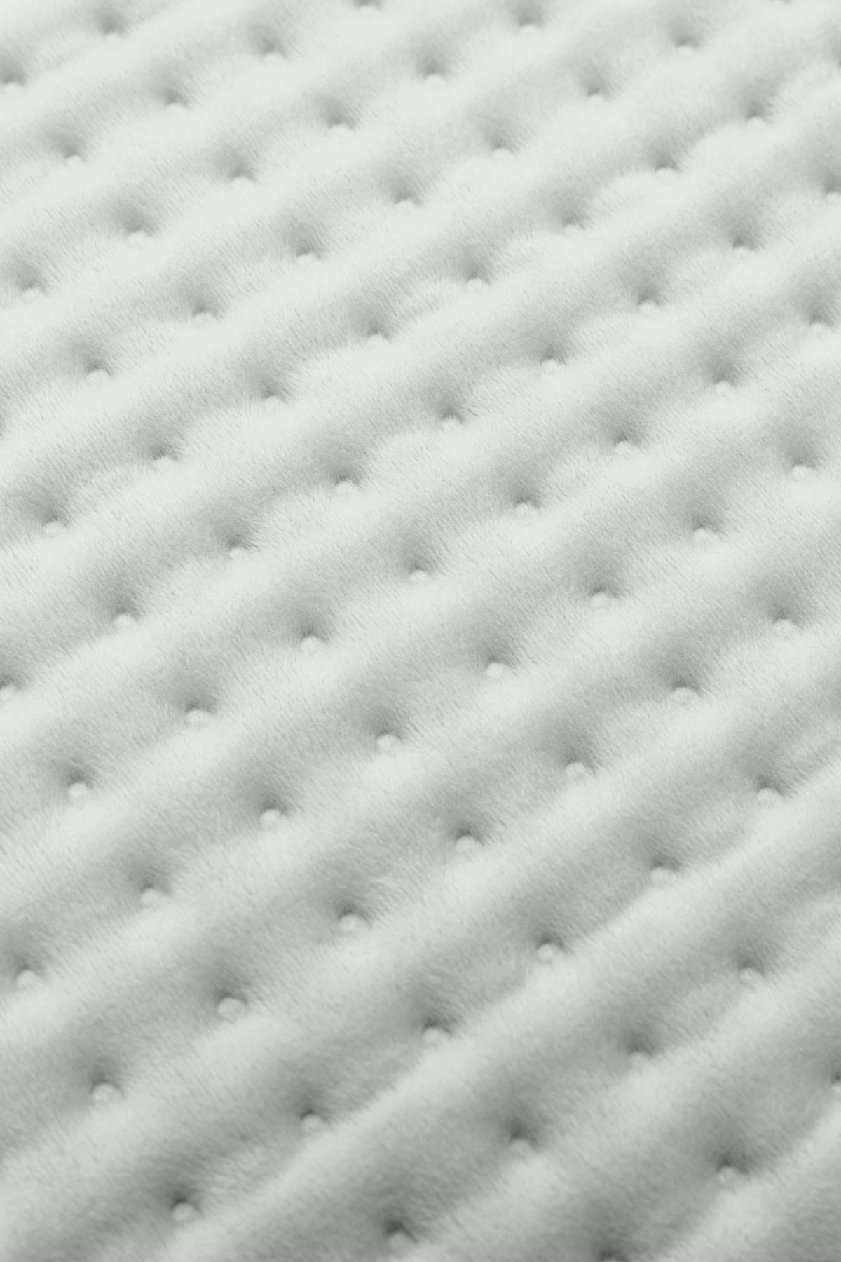 Primer plano de una tela acolchada, suave, texturizada, de color verde claro.