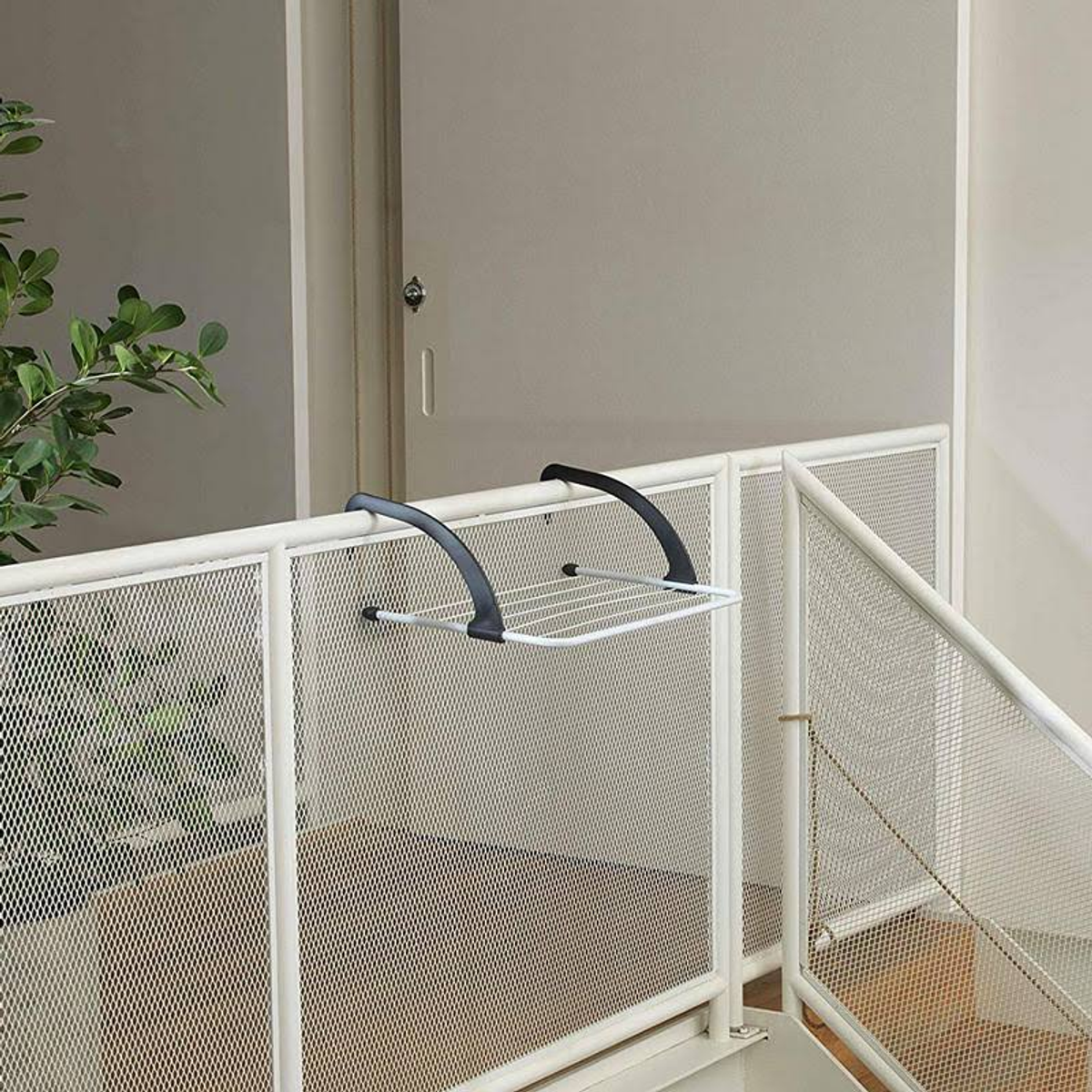 Biały metalowy stojak na pranie przymocowany do białej balustrady na balkonie, na zewnątrz, ze schodami.