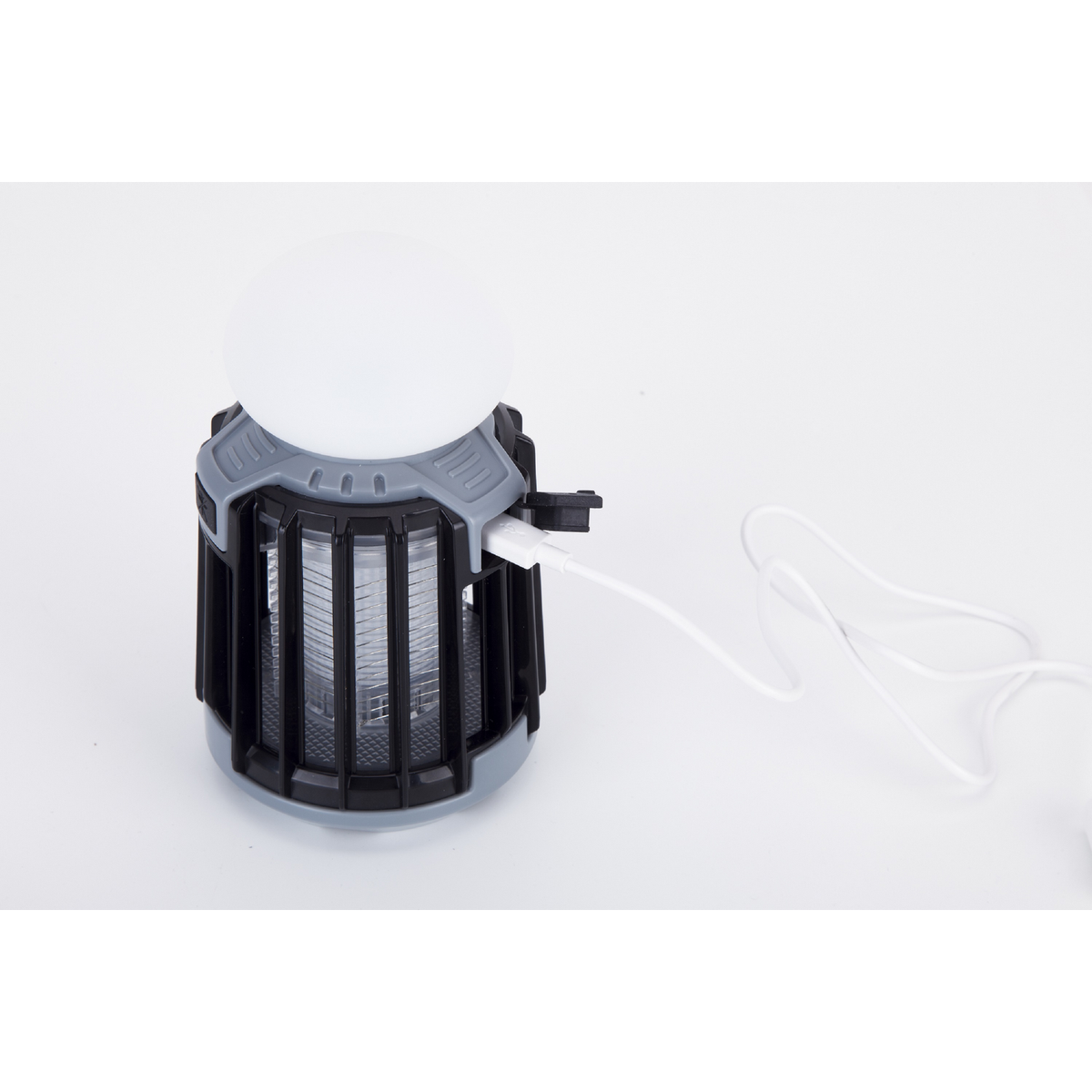 Una linterna de carga con cable blanco, sobre una superficie blanca. Es negro y gris.