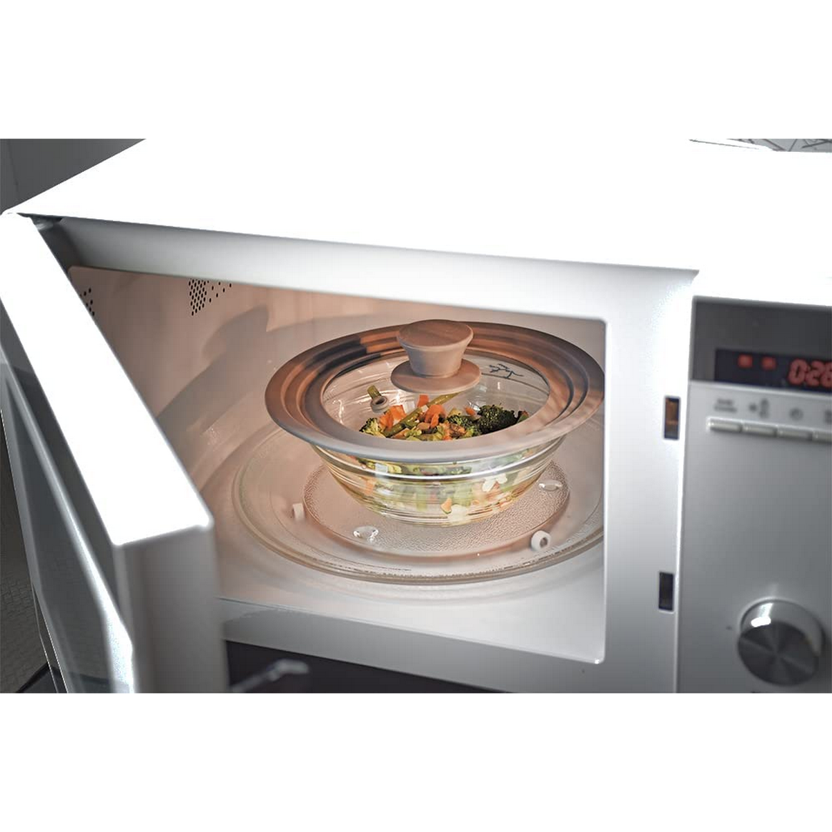 Microondas con la puerta abierta, mostrando un bol de cristal con verduras dentro.