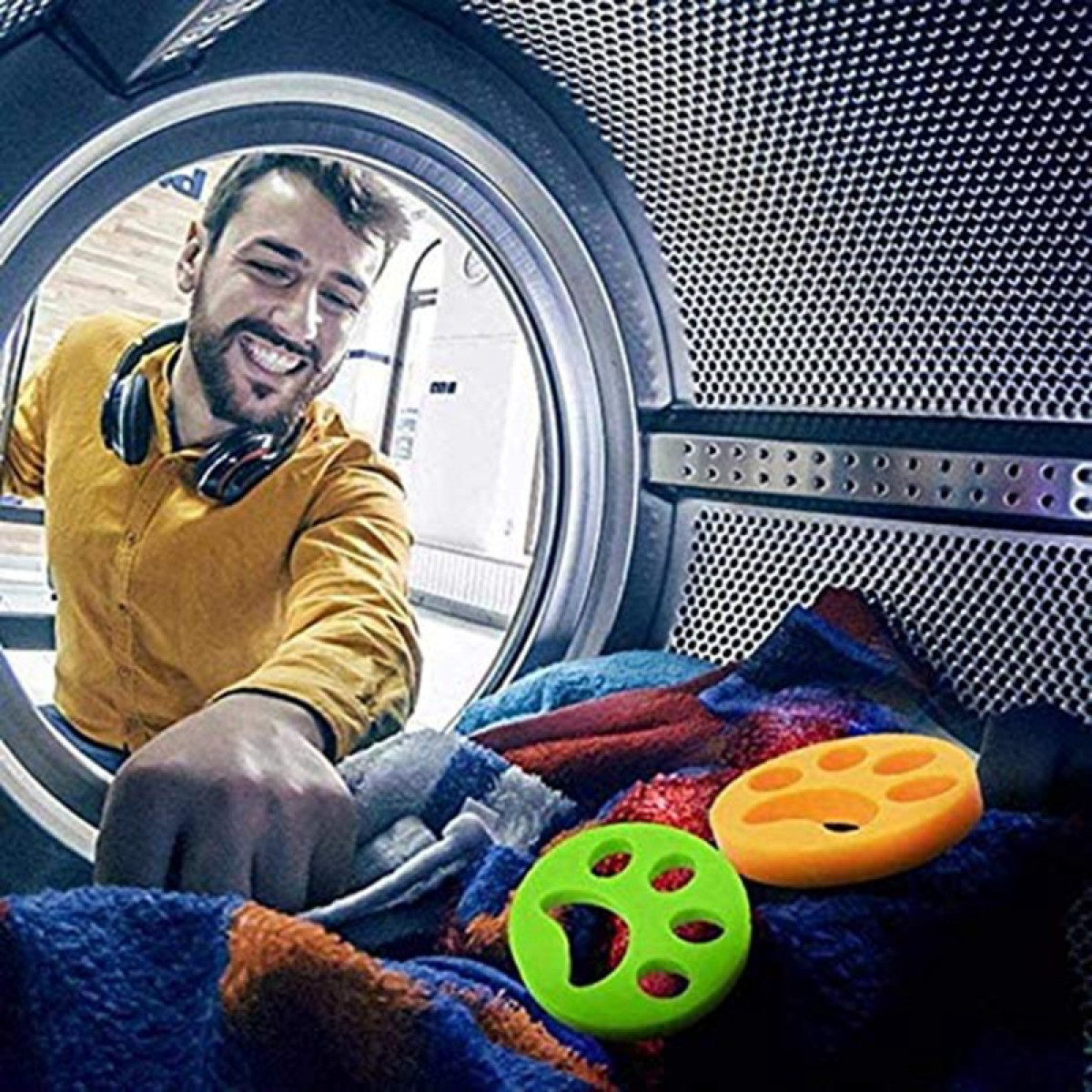 Hombre sonriendo, poniendo artículos de lavandería en una lavadora.
