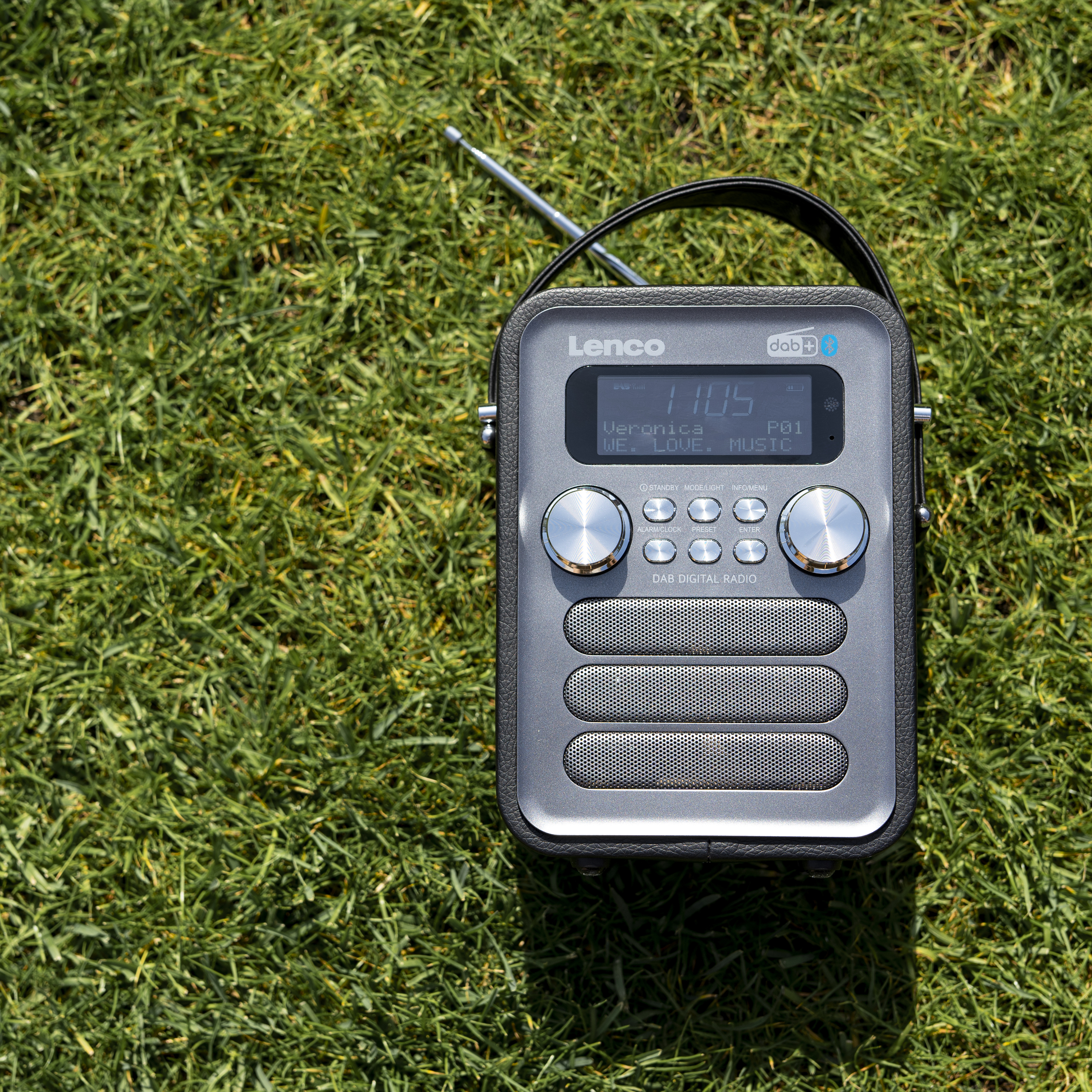 Szaro-czarne radio przenośne na trawie.