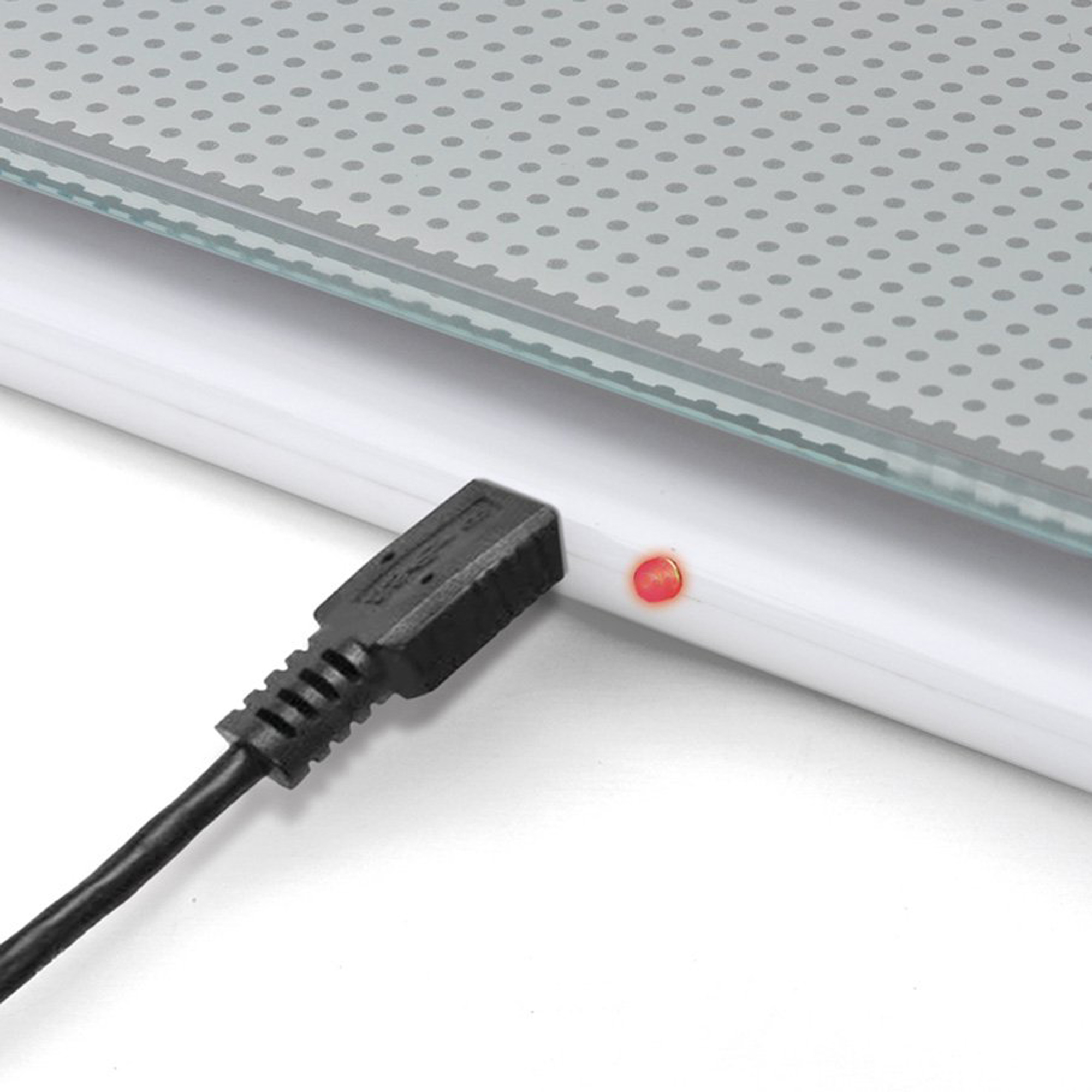 Biała waga elektroniczna z podłączonym czarnym kablem USB. Czerwone światło wskazuje ładowanie.