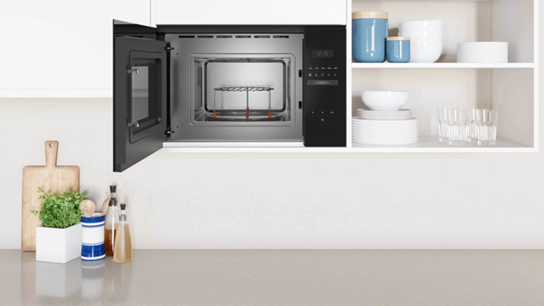 Kuchenka mikrofalowa otwarta na blacie kuchennym, z różnymi przedmiotami kuchennymi wokół.