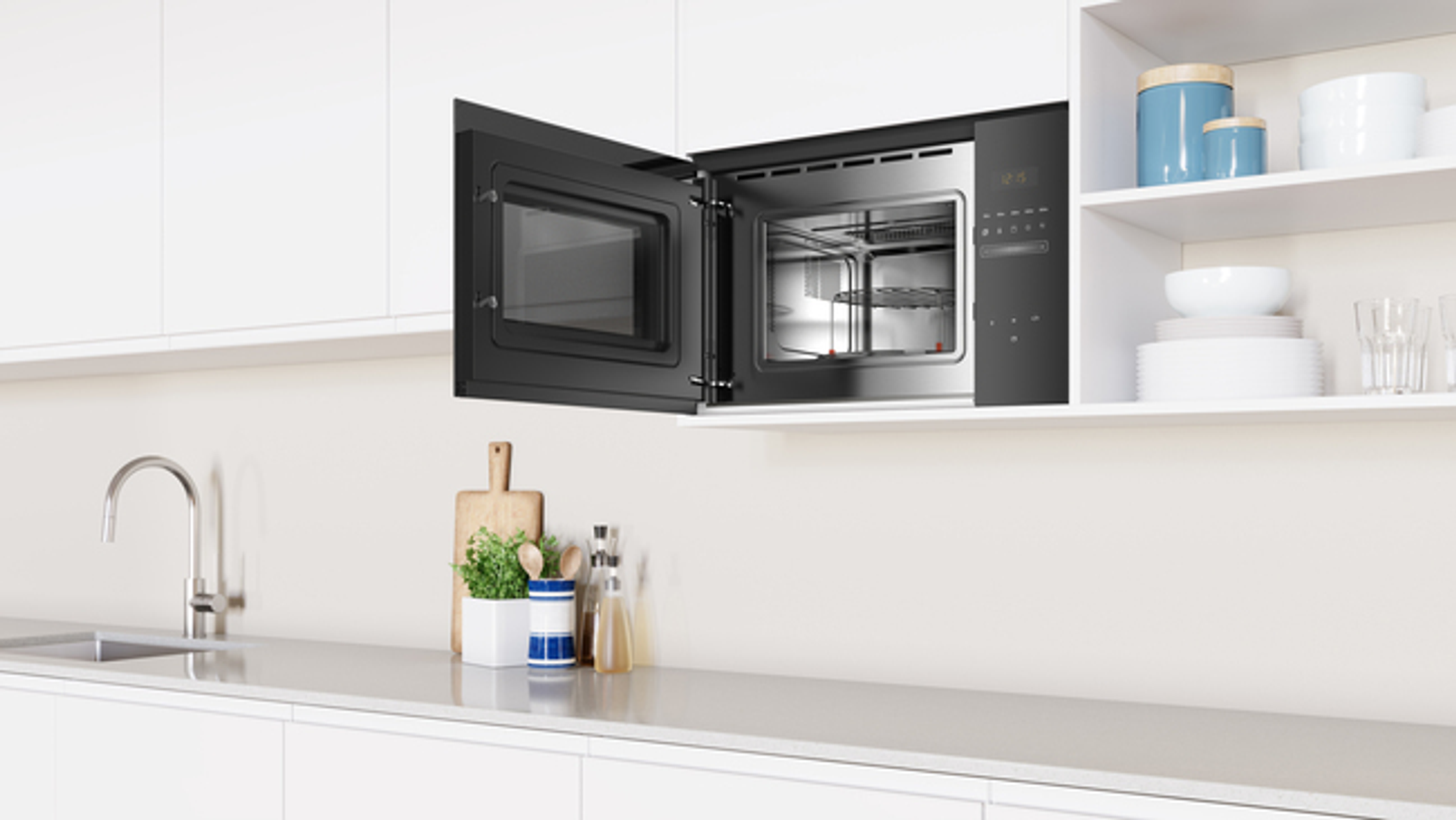 Otwarta czarna kuchenka mikrofalowa zamontowana w białej kuchni. Kuchnia zawiera zlew i blat.