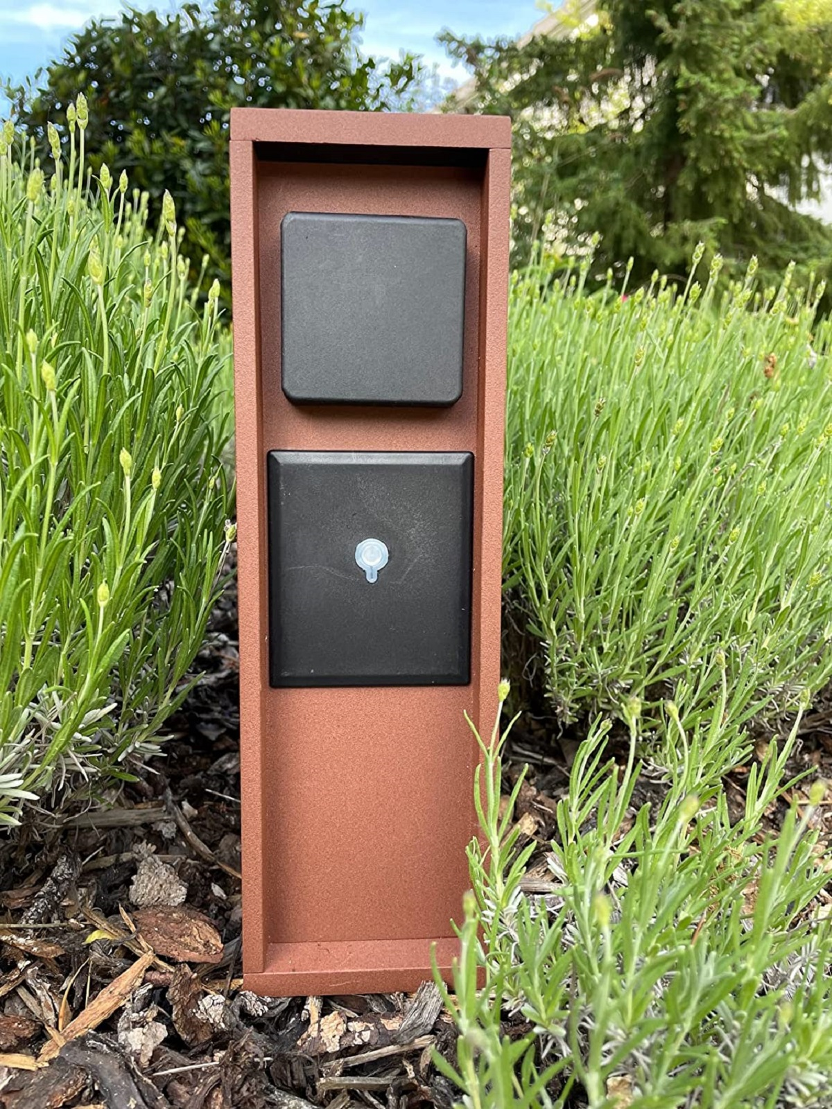 Eine braune Außensteckdose in einem Garten.