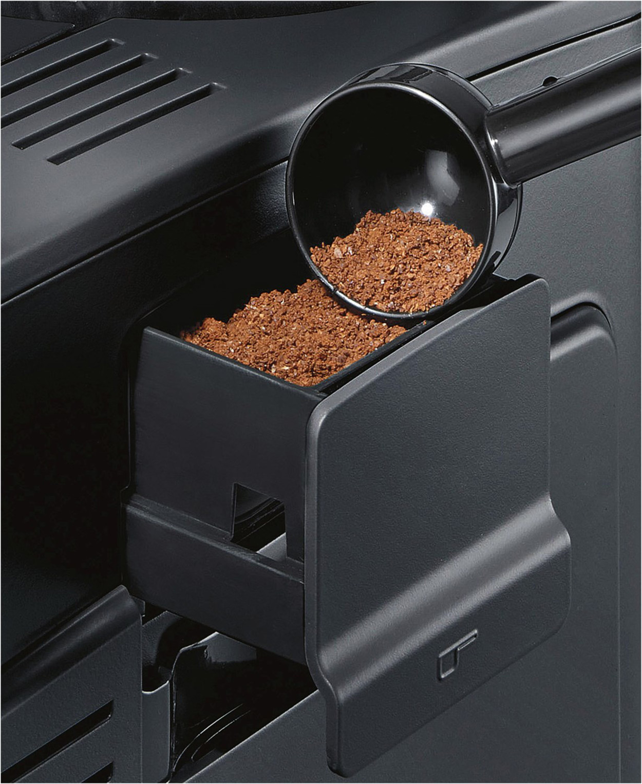 Kaffeemaschine mit Löffel, der Kaffeepulver in eine Schublade gießt.