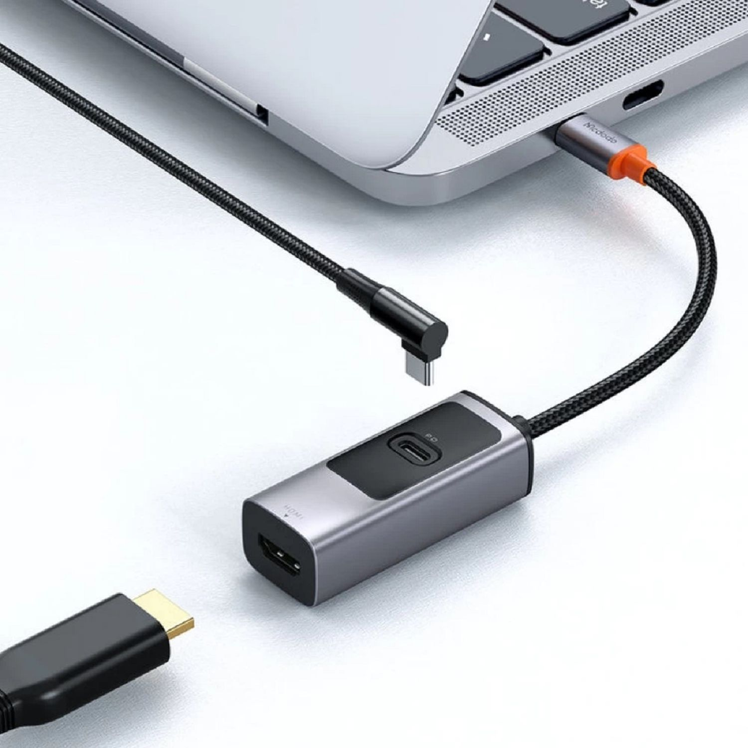 Laptop, verbunden mit einem silbernen Adapter, dann mit einem schwarzen HDMI-Kabel. Adapter hat orange Spitze.