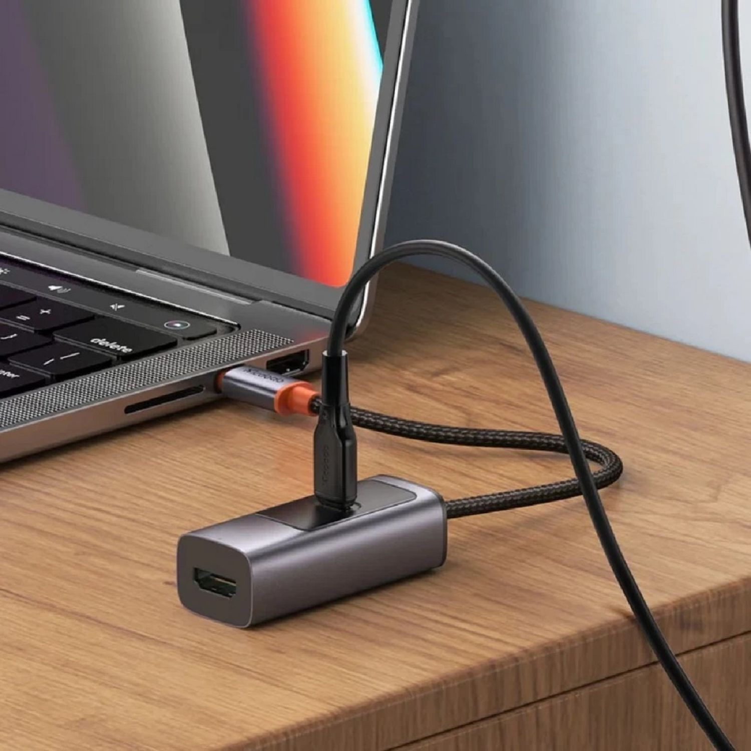 Ein silberner Hub, der mit einem Laptop verbunden ist. Ein schwarzes Kabel verbindet den Hub mit einem anderen Gerät.