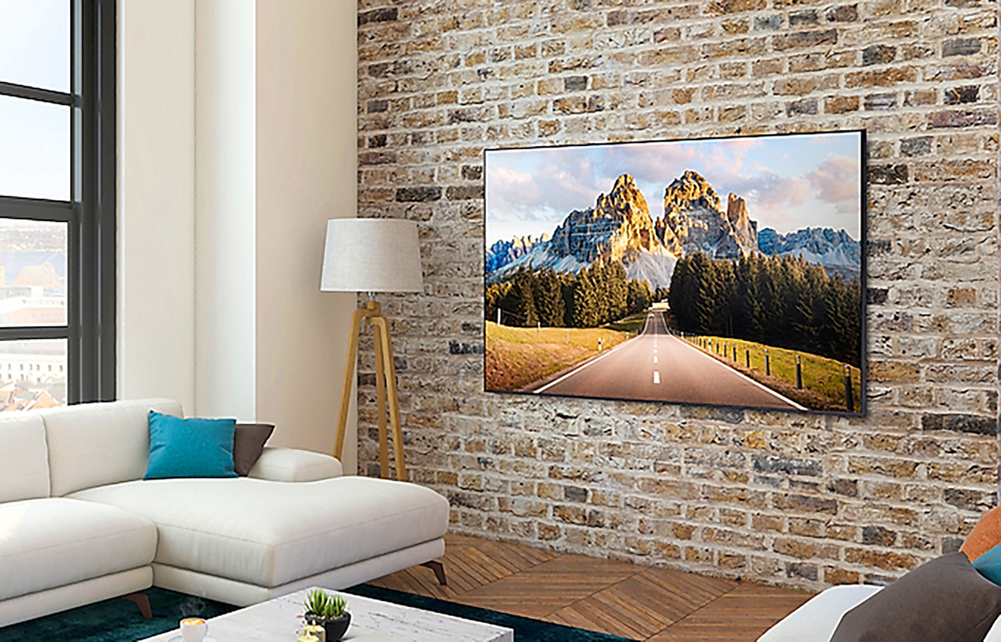 Salon z telewizorem na ceglanej ścianie, białą sofą i lampą podłogową.