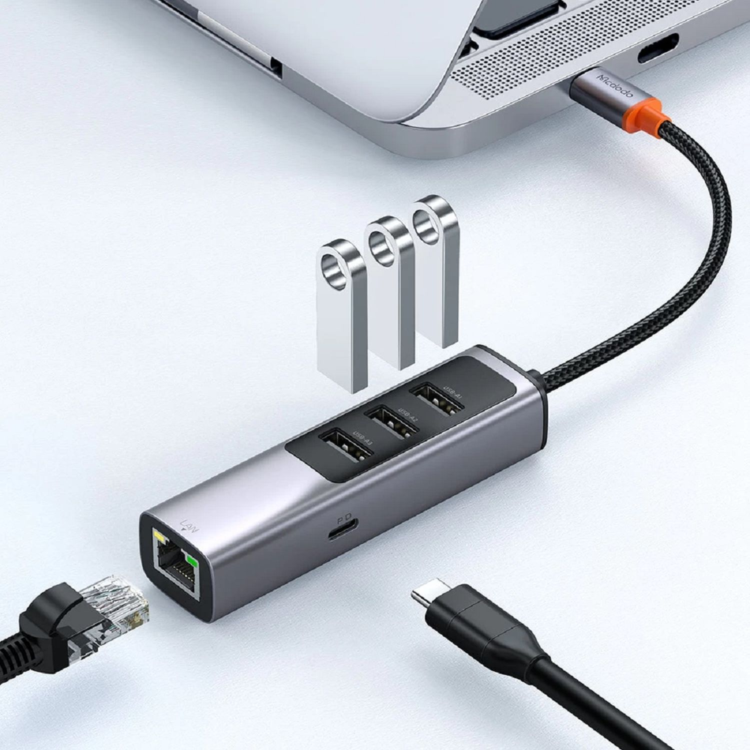Silberner Hub mit USB-Anschlüssen, LAN-Anschluss und USB-C-Anschluss, der an einen Laptop angeschlossen ist.