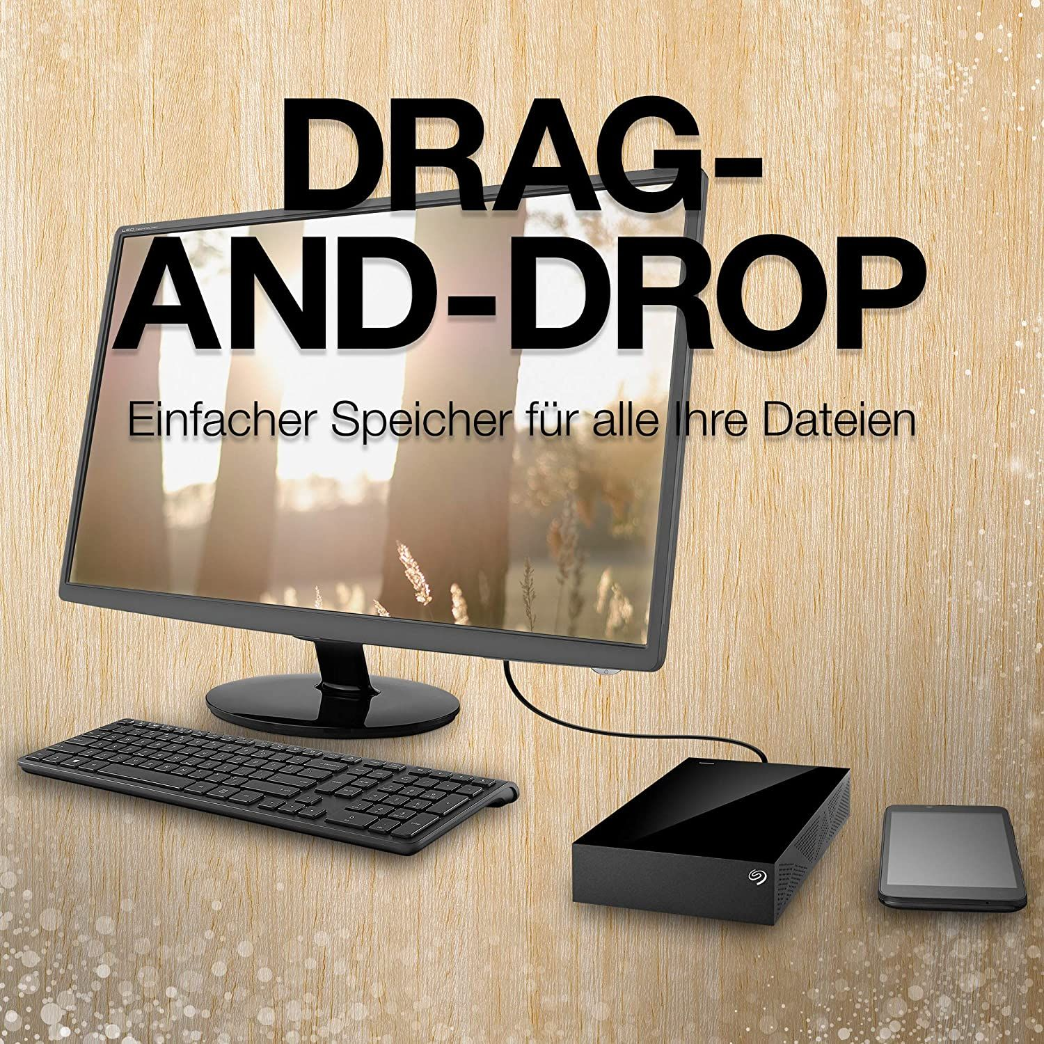 Ein Computer-Setup mit Monitor, Tastatur und Festplatte. Der Text auf dem Monitor lautet DRAG-AND-DROP.