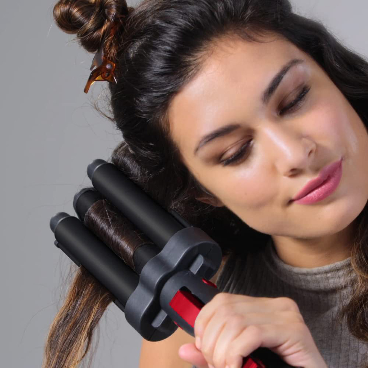Frau benutzt einen Haarwellenmacher, Werkzeug und Haare sind im Fokus.