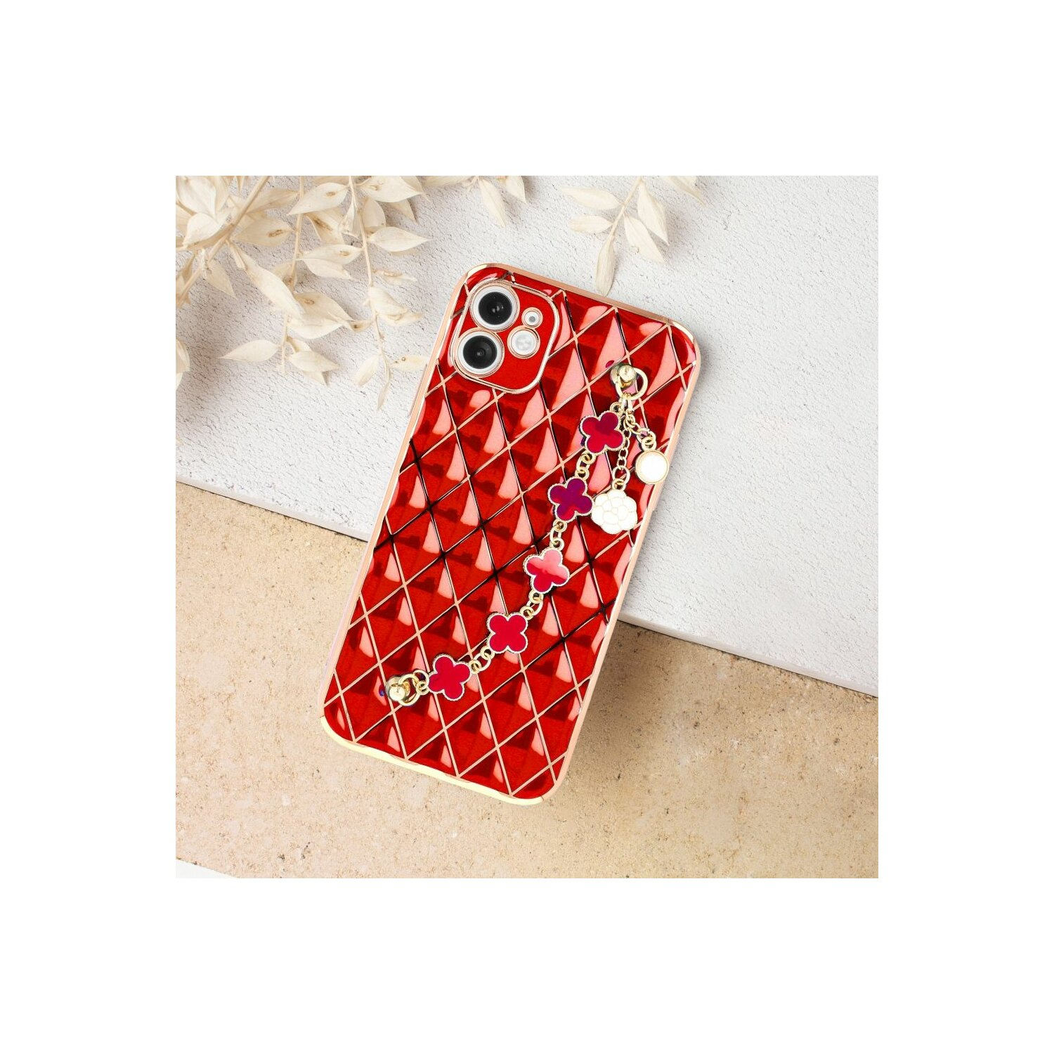 Custodia per telefono rossa con motivo a diamante e un ciondolo. Il ciondolo ha fiori e perline.