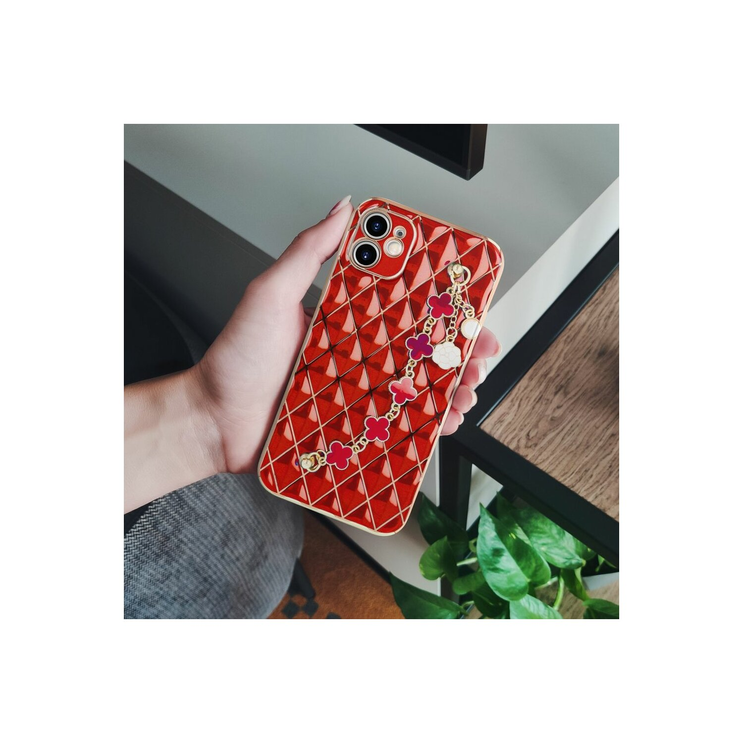 Mano che tiene una cover rossa a rombi e un ciondolo.