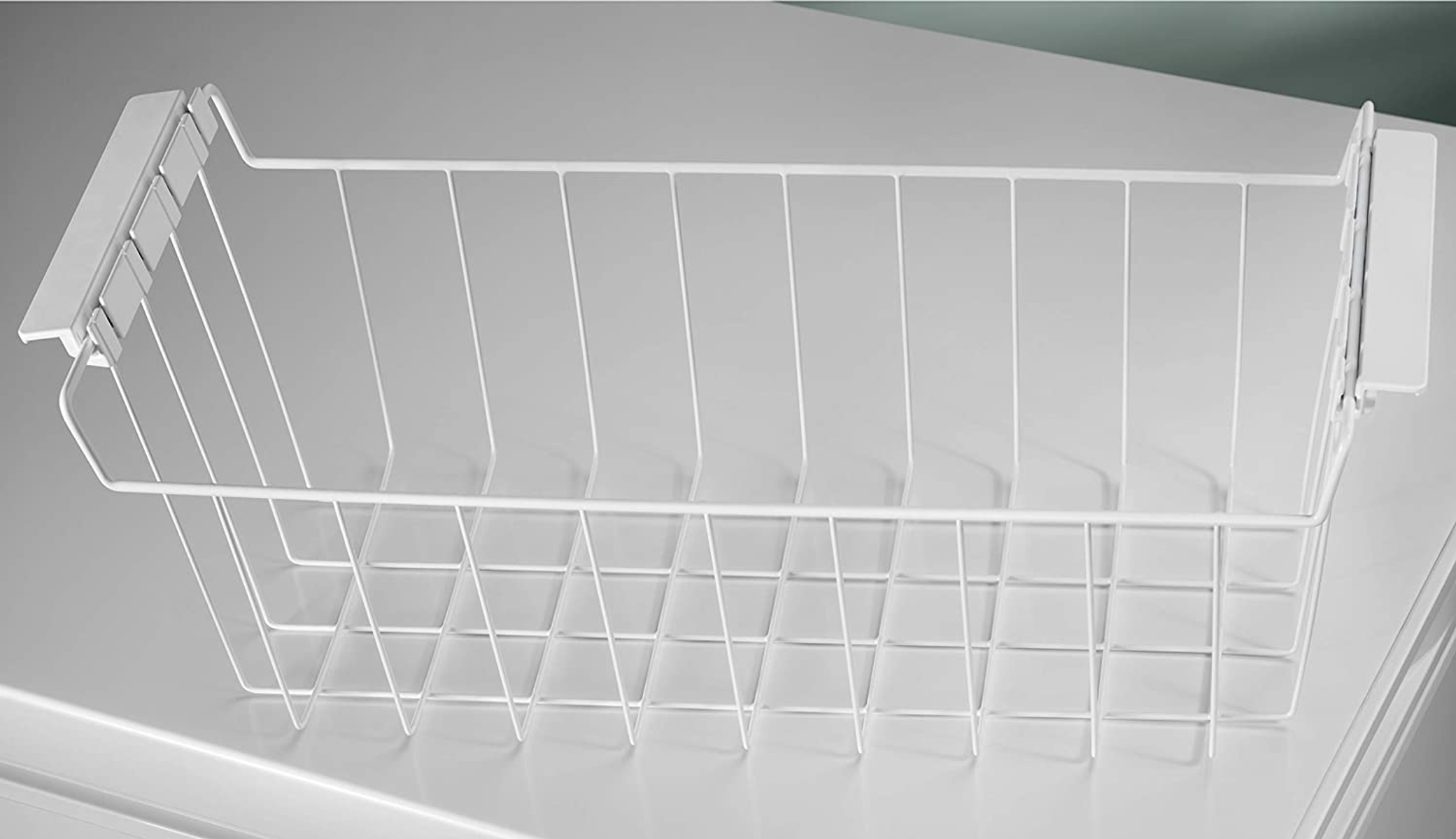 Un cestello per frigorifero in filo bianco. È aperto e pronto per l'uso.
