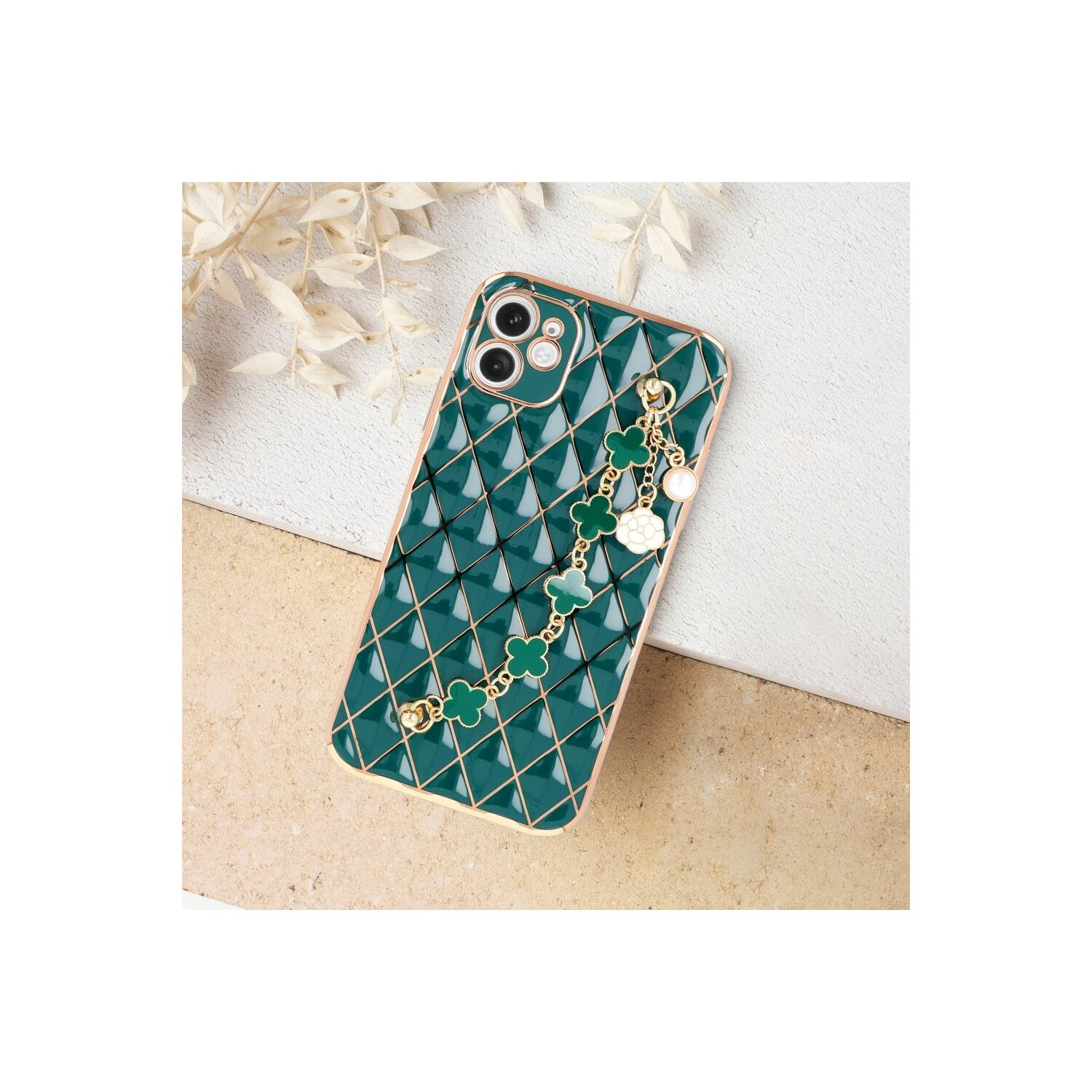 Una custodia verde per telefono con motivo a diamante e una catena con ciondoli, appoggiata su una superficie.