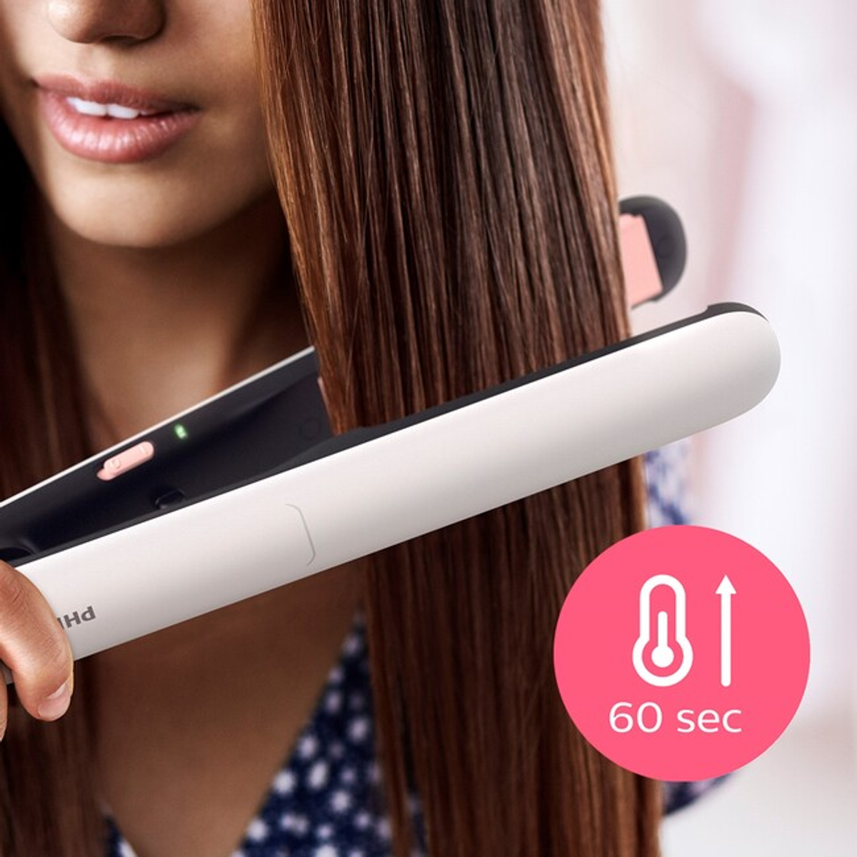 Donna che si liscia i capelli con una piastra Philips bianca e rosa. Testo: 60 secondi.