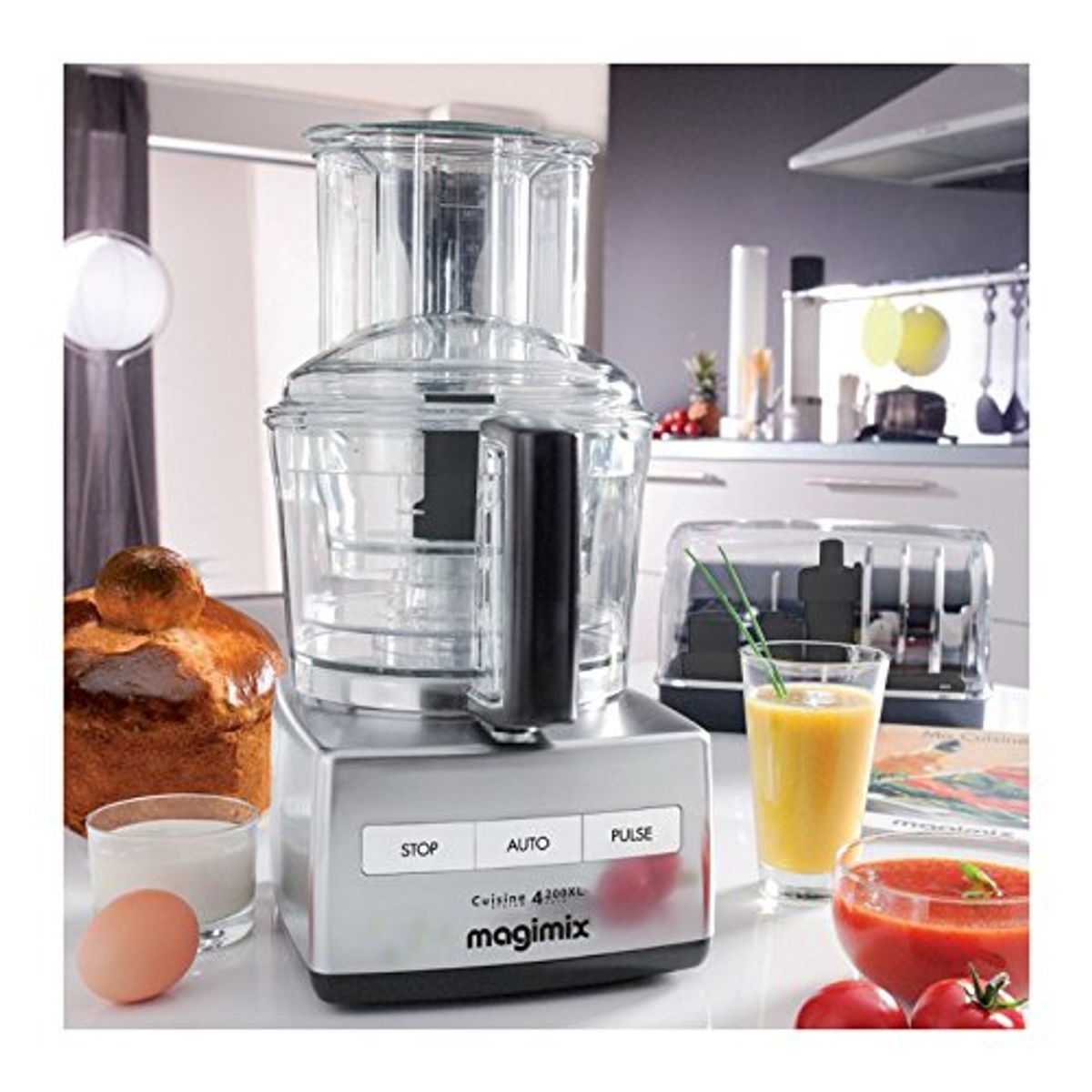 Robot da cucina con ingredienti intorno. Include una torta, latte, un uovo e pomodori.