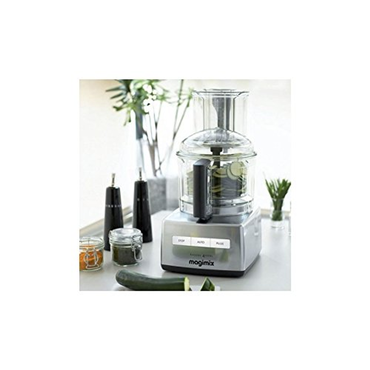 Un robot da cucina con verdure all'interno e altri utensili da cucina su un bancone.