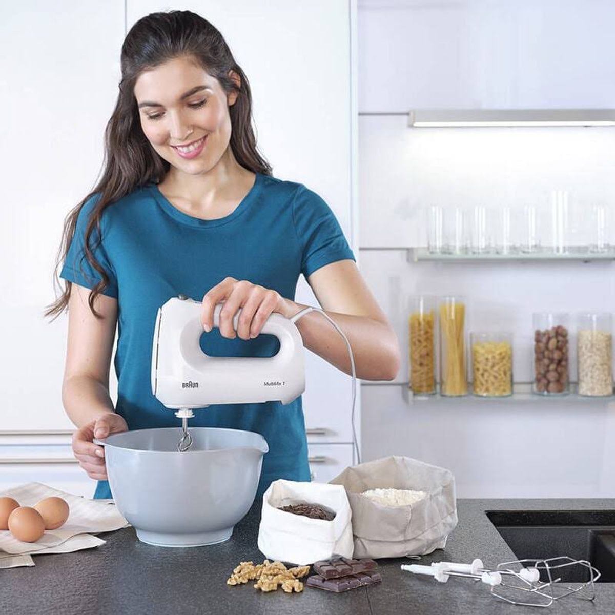 Frau benutzt einen weißen Handmixer mit Eiern, Mehl und Zutaten.