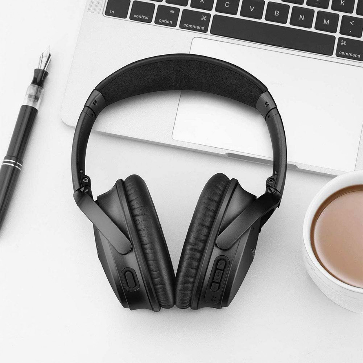 Czarne słuchawki na białej powierzchni, z laptopem i filiżanką kawy.