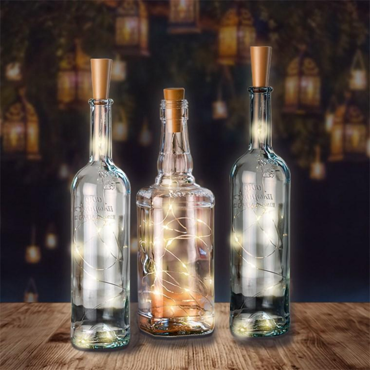 Drei Glasflaschen mit Lichterketten auf einer Holzoberfläche.