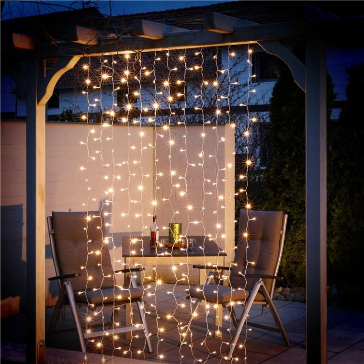 Ambientazione esterna con luci a catena e un tavolo per cenare.