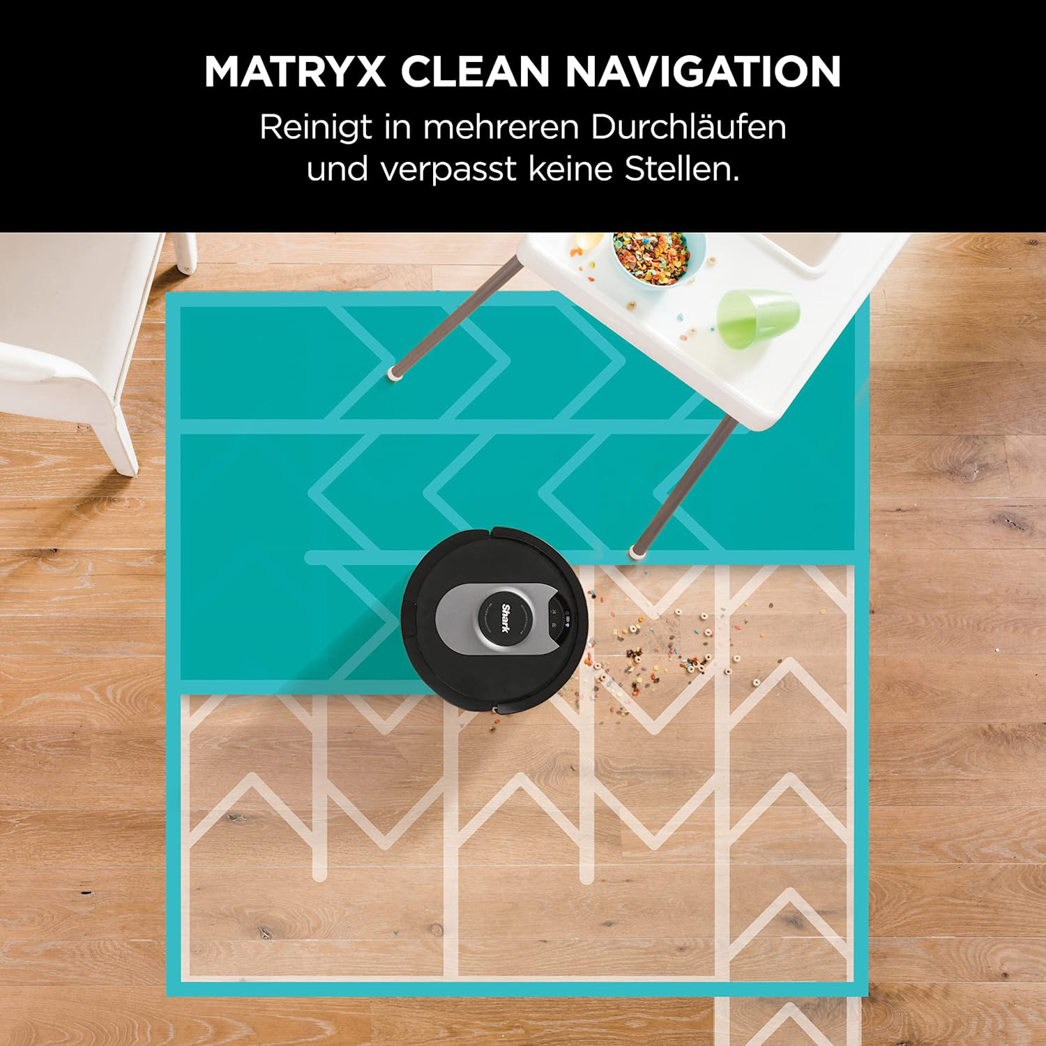 Robot sprzątający czyszczący wzorzysty dywan. Podłoga jest drewniana, a w tle znajduje się stół.