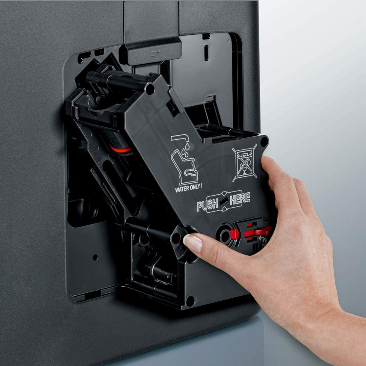 Hand inserting a black coffee machine component with a red element into a black machine.