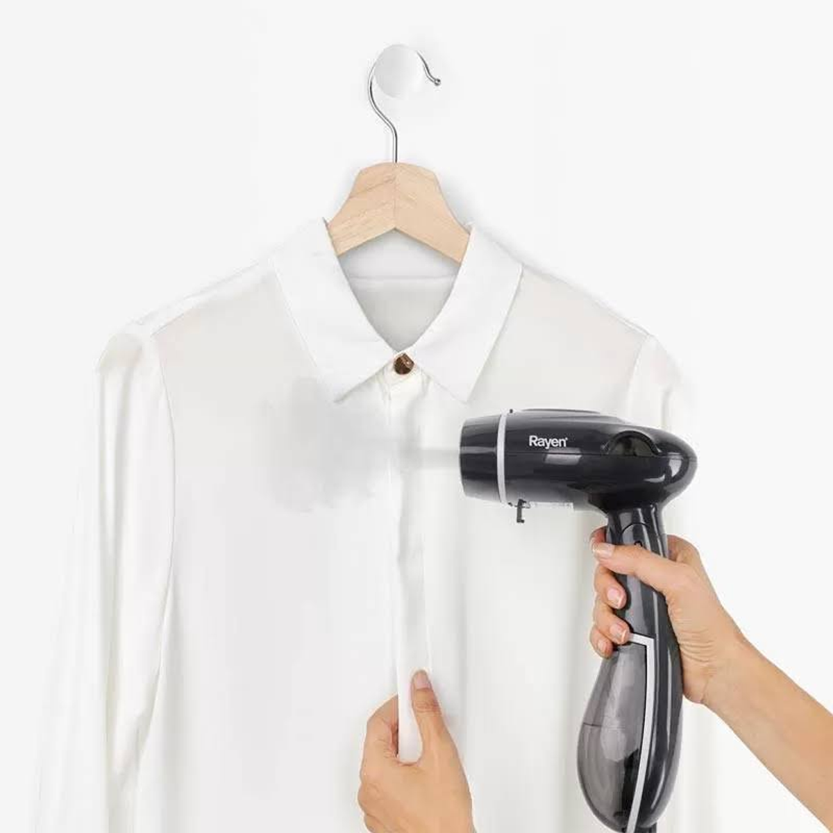 Un vaporizzatore per indumenti nero e argento vaporizza una camicia bianca.