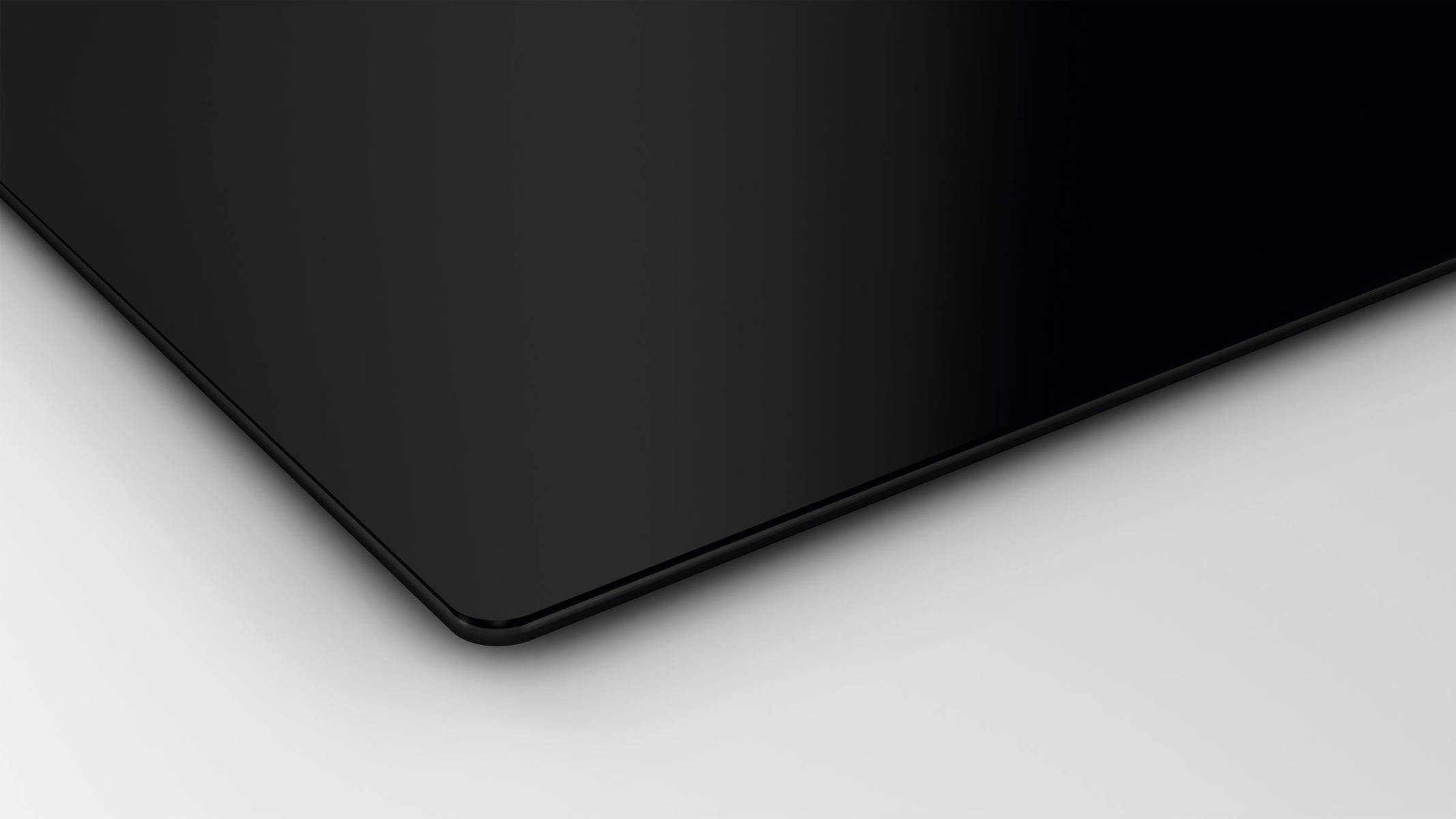 Czarna płyta ceramiczna. Gładka, błyszcząca powierzchnia. Na białym tle. Lekki widok z kąta.