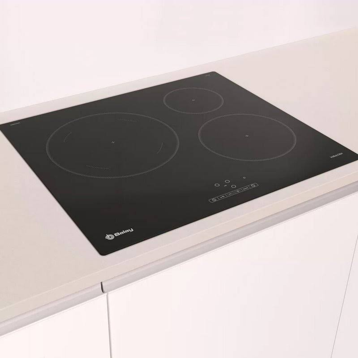 Czarna płyta indukcyjna na białym blacie, z trzema okrągłymi strefami gotowania.