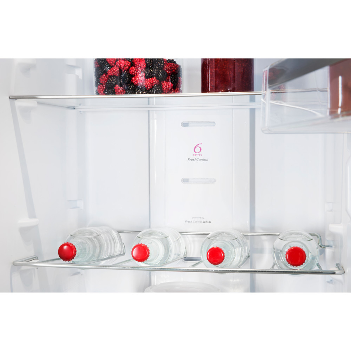 Wewnątrz lodówki: półki z butelkami wody i słoikami z owocami.