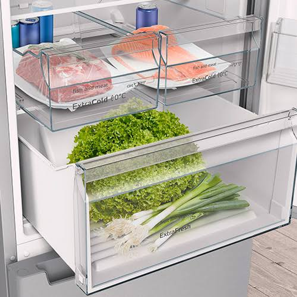 Interior de un refrigerador con productos frescos y carne envasada. Lechuga y cebolletas en un cajón.