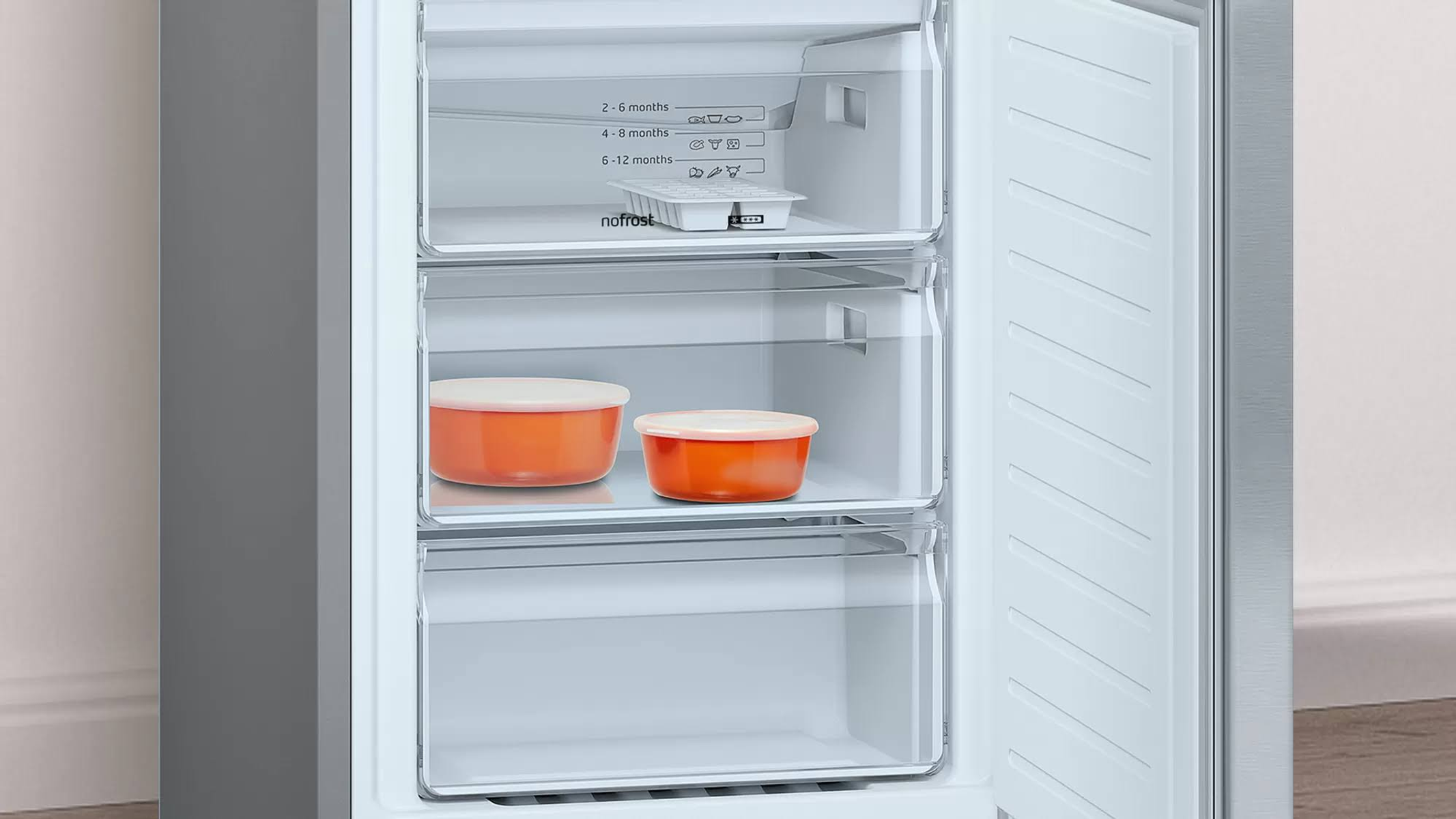 Congelador con la puerta abierta. Dentro hay tres cajones transparentes y recipientes naranjas.