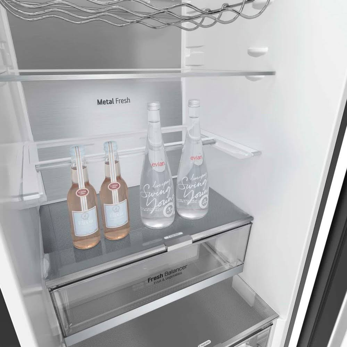 Dentro de un refrigerador. Hay botellas de agua Evian y bebidas Elixir en los estantes.
