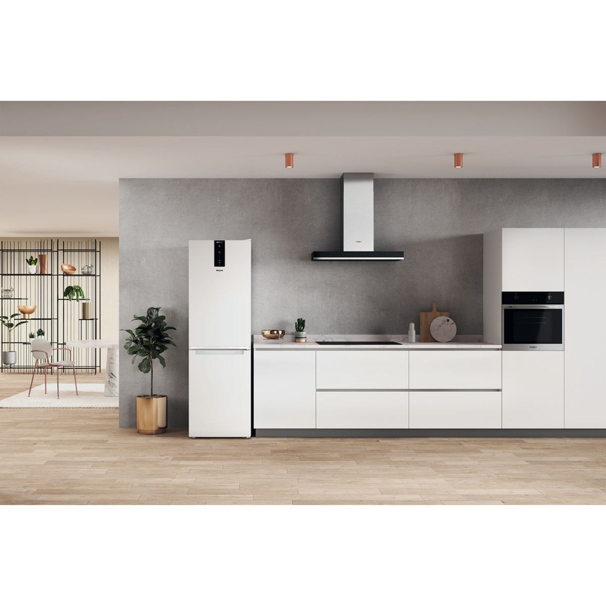 Cocina blanca con nevera, horno y armarios. Suelo de madera y pared gris.