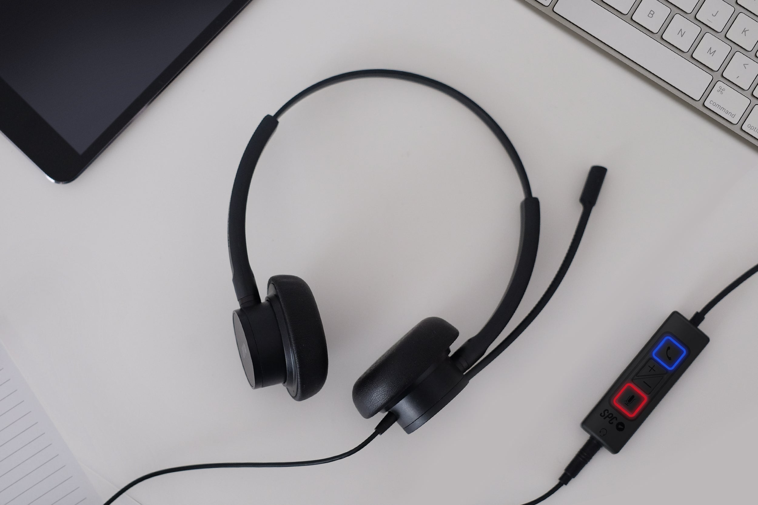 Vista superior de unos auriculares SPC negros, con panel de control y tableta.