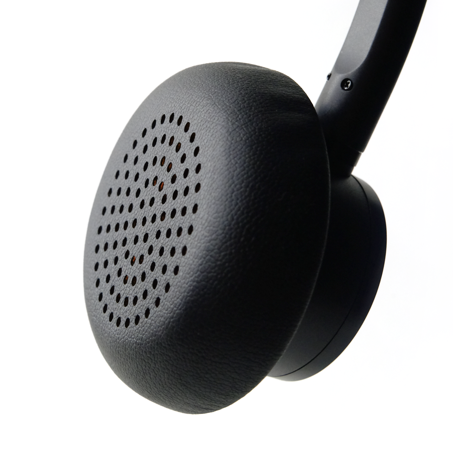 Auricular de auriculares negro, primer plano, con perforaciones. Fondo blanco.
