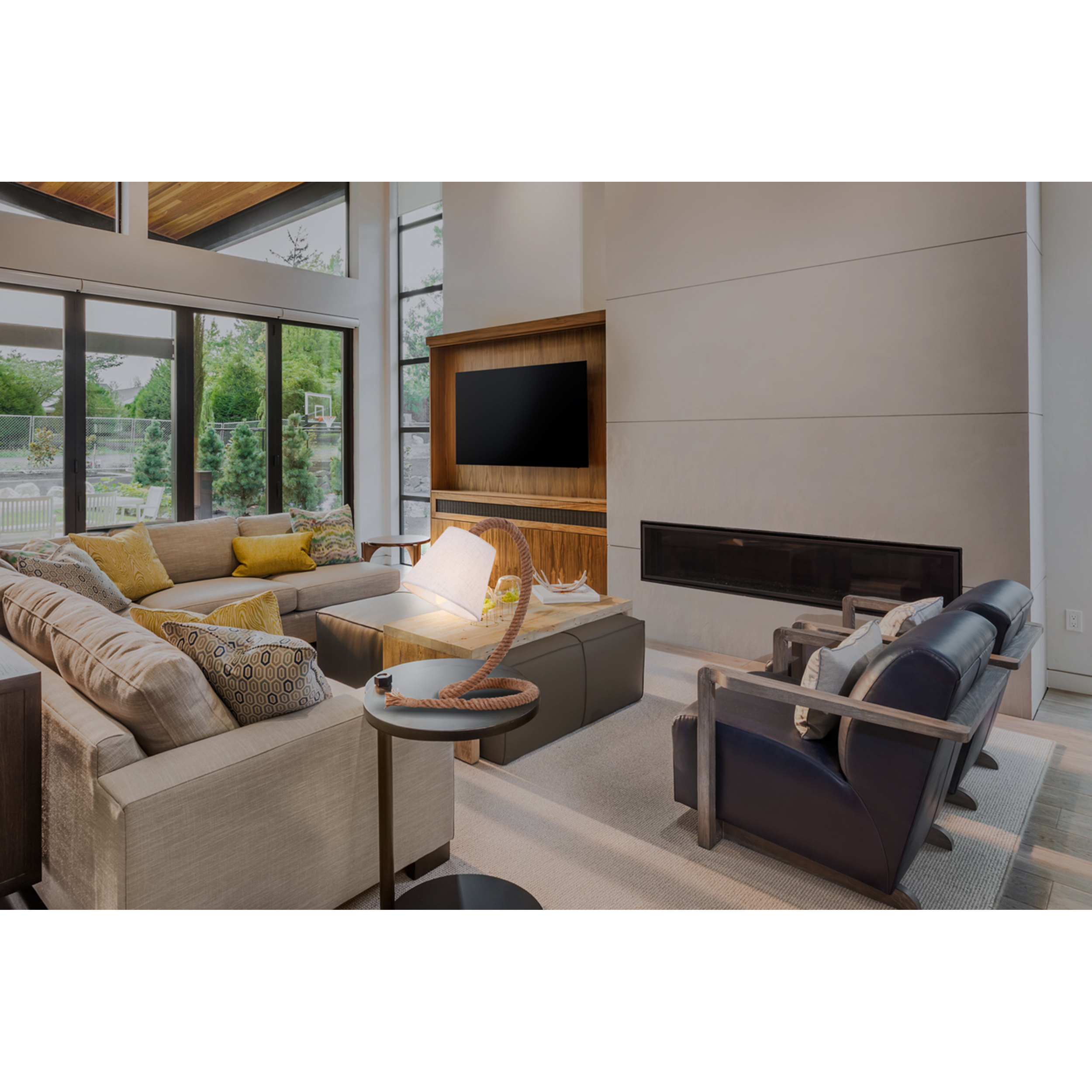 Ein modernes Wohnzimmer mit beigem Sofa, grauen Stühlen und einem TV.