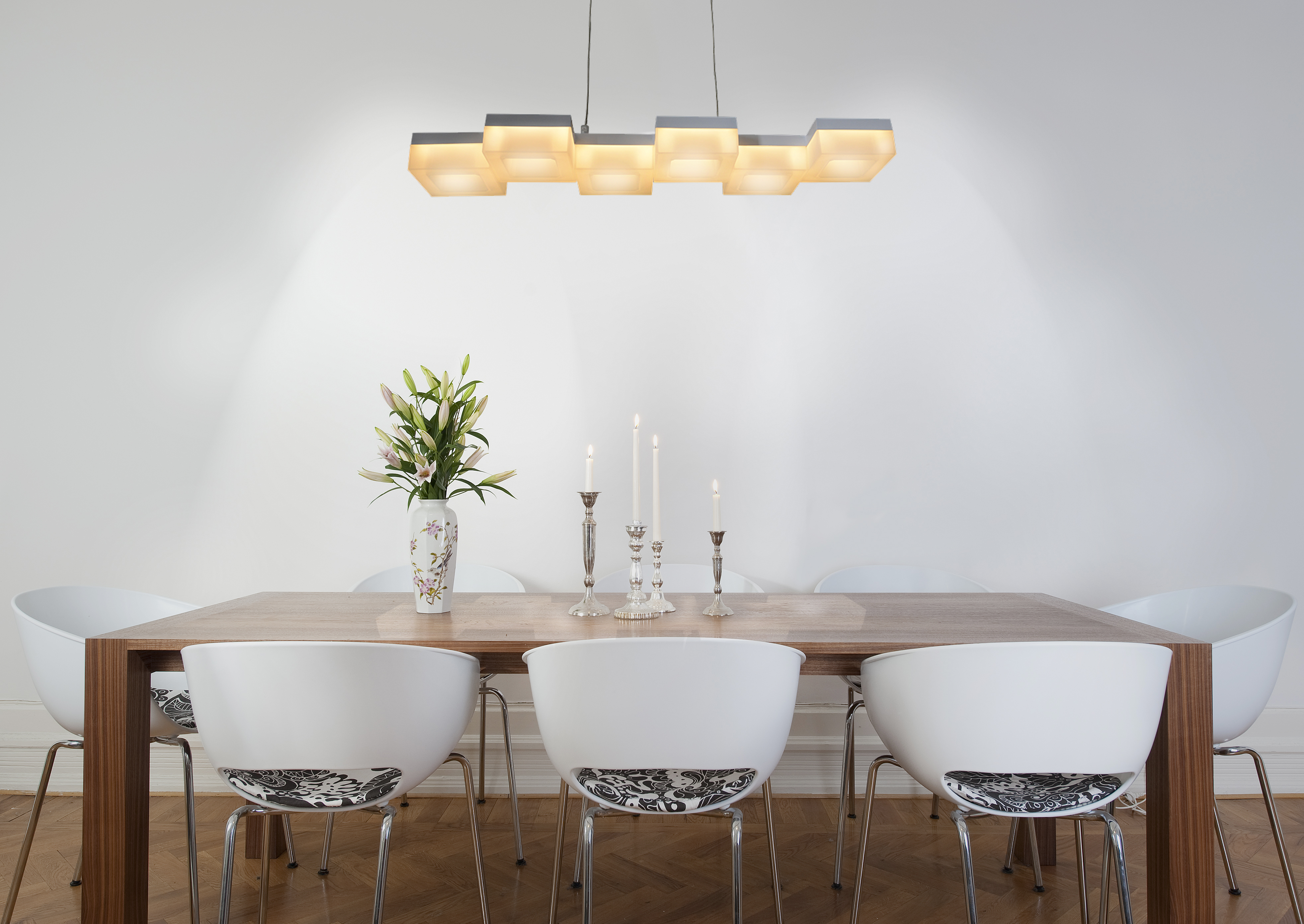 Modernes Esszimmer mit weißen Stühlen, Holztisch und Deckenbeleuchtung.