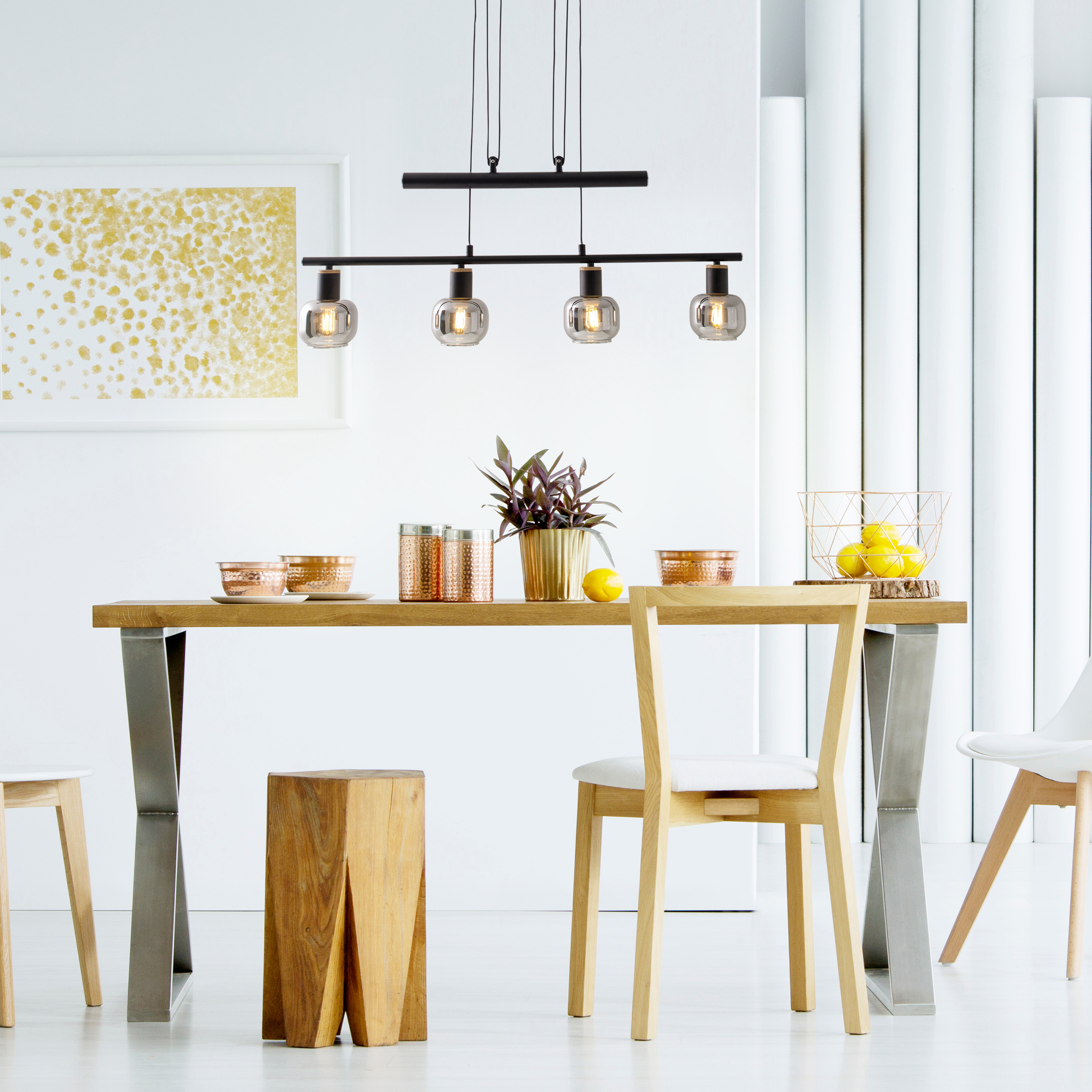 Sala da pranzo con tavolo in legno, sedie e lampada a sospensione. Include oggetti decorativi e parete bianca.