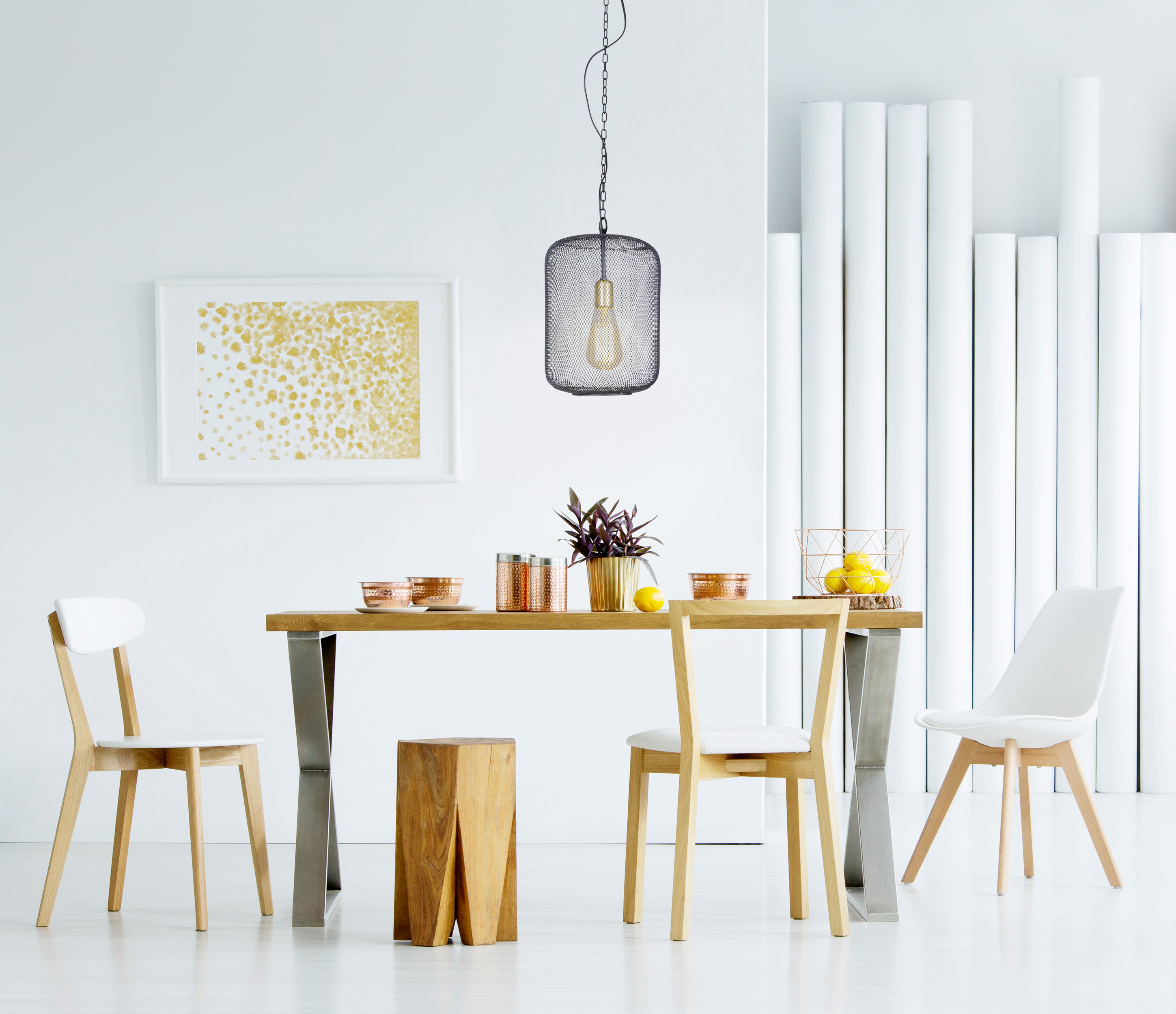 Ein Esszimmer mit Tisch, Stühlen und einer Hängeleuchte. Weiße Wände und Boden.