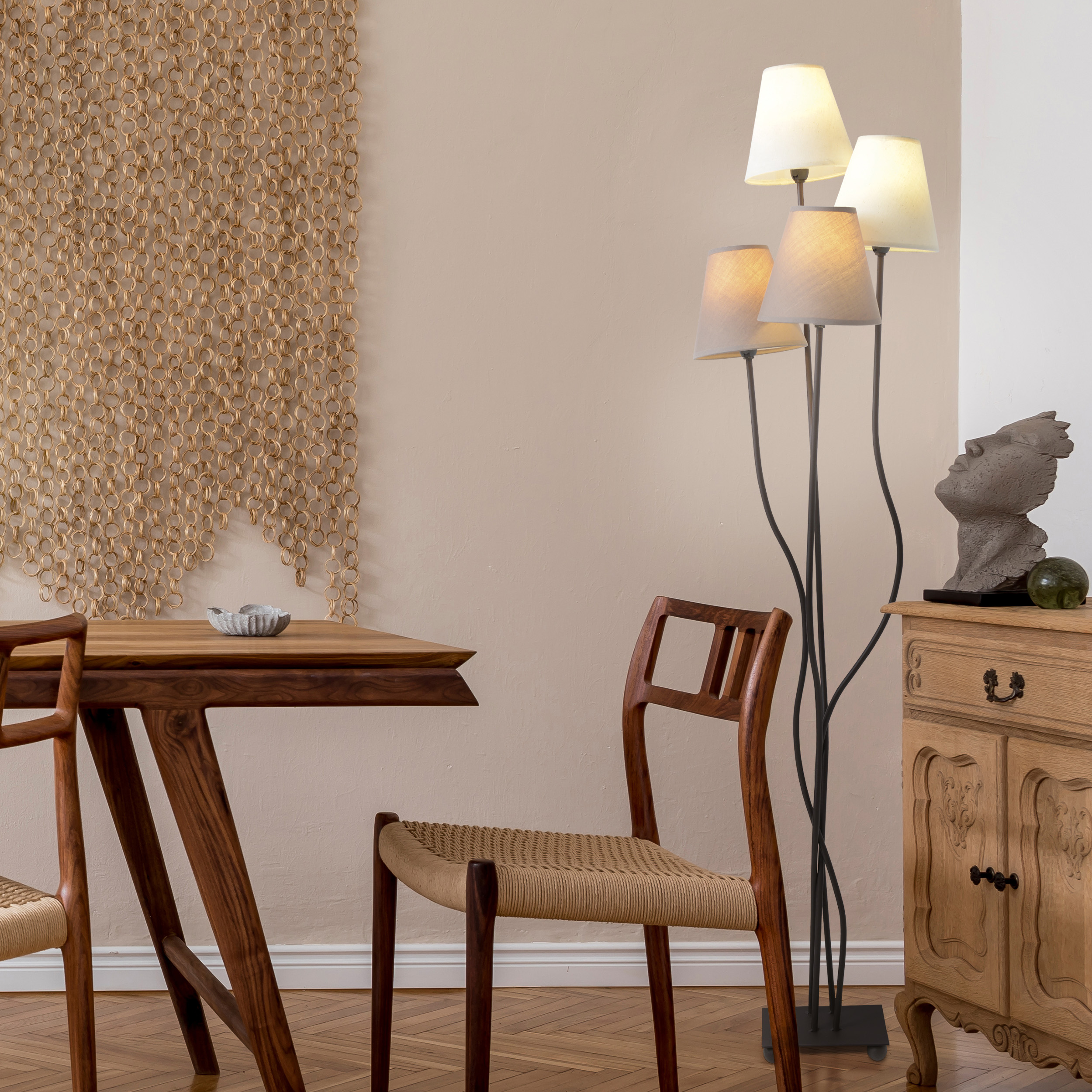 Innenraum mit Holzmöbeln: Tisch, Stühle, Schrank. Eine Stehlampe und eine Wanddekoration sind vorhanden.
